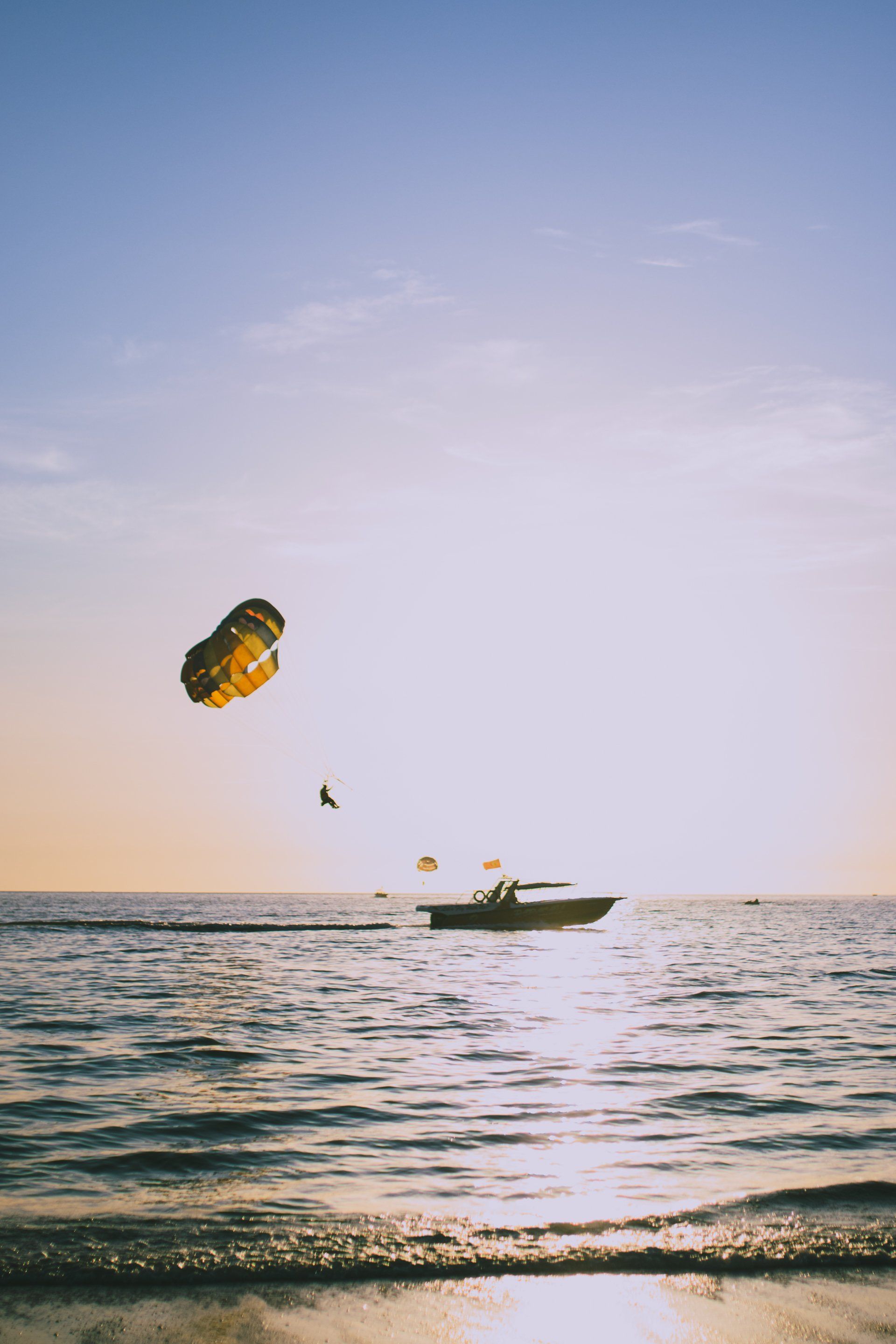 a person is parasailing over the ocean with a boat in the background .