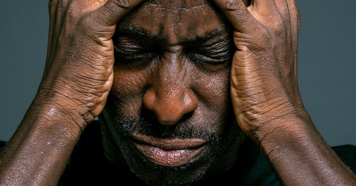 A man is holding his head in his hands and crying.