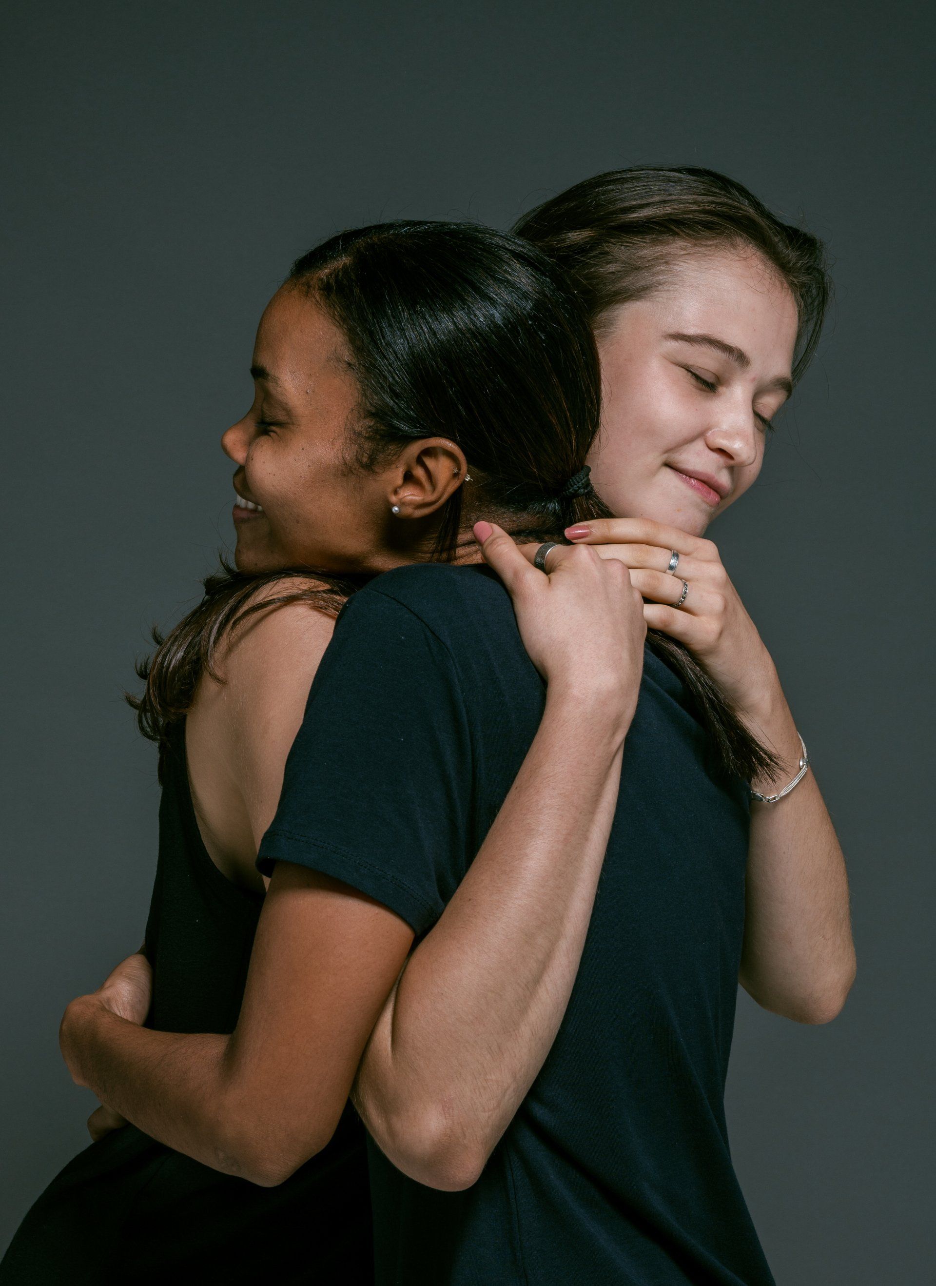 Two women are hugging each other back to back.