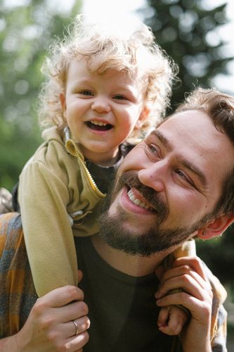 A man is carrying a little boy on his shoulders.