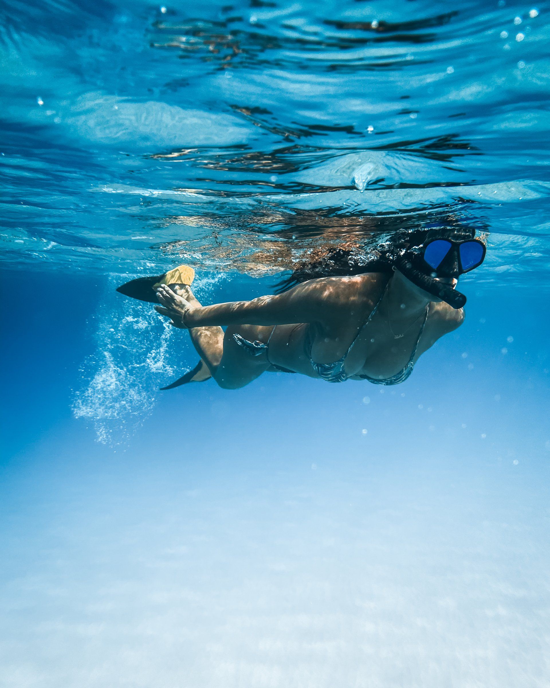 A woman in a bikini is swimming underwater in the ocean.