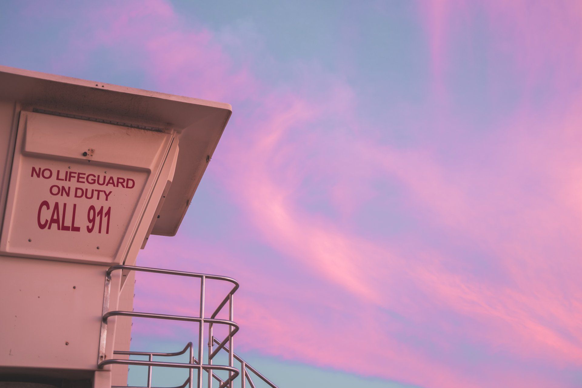 A lifeguard tower with a pink sky in the background.