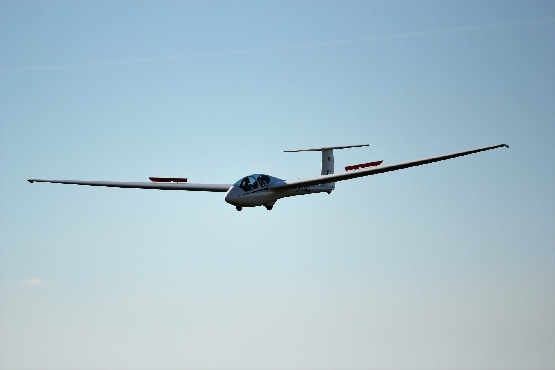 A glider is flying through a clear blue sky
