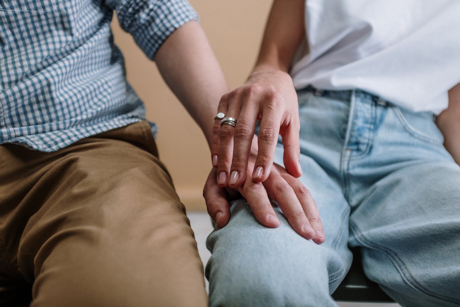 A man and a woman are holding hands while sitting next to each other.
