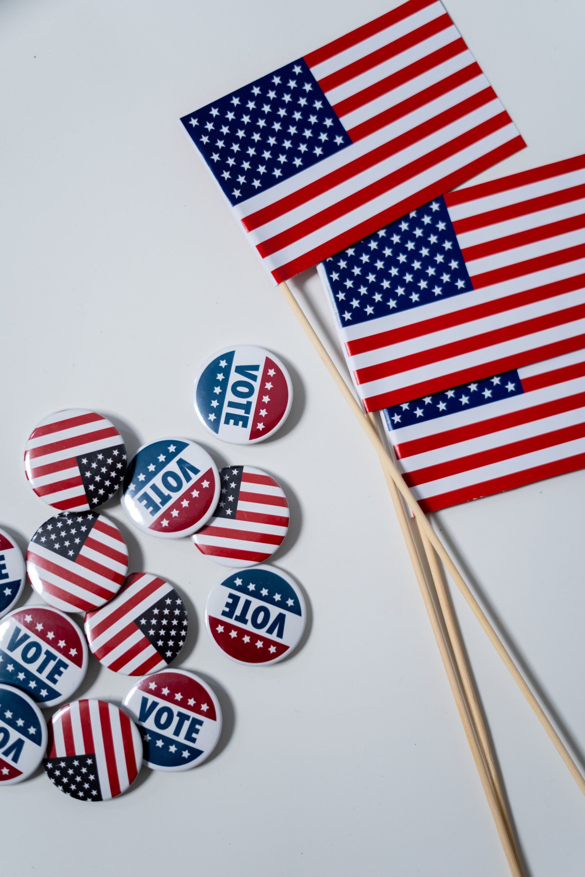 USA flags and USA voting  shirt pins lying on white surface