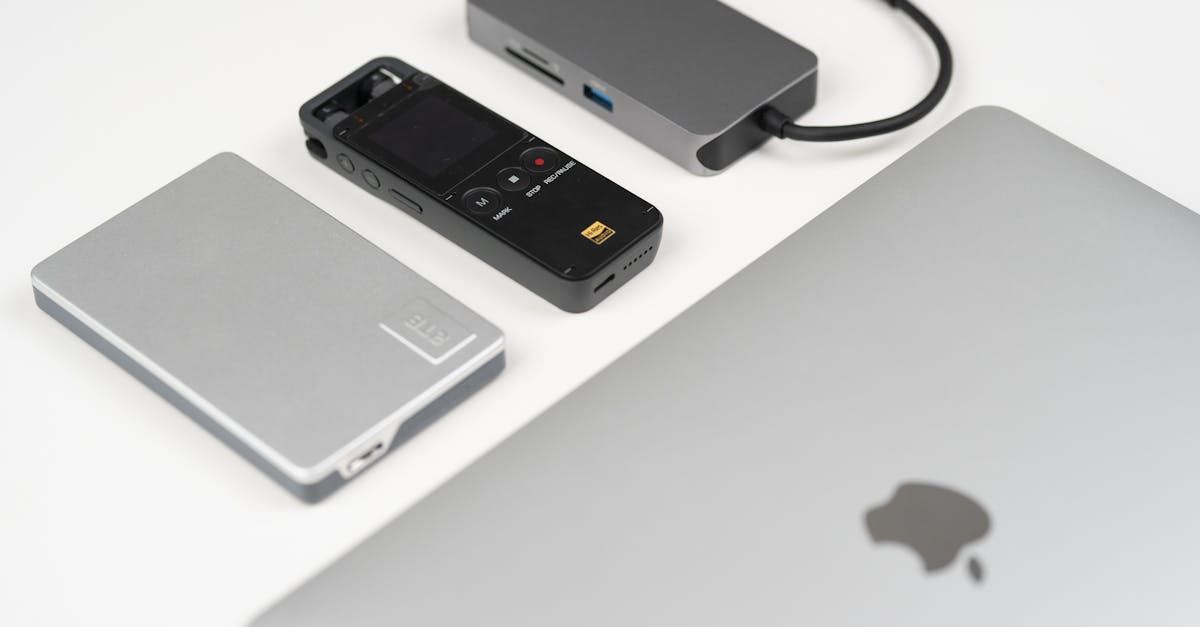 A laptop , a power bank , and a remote control are sitting on a table.