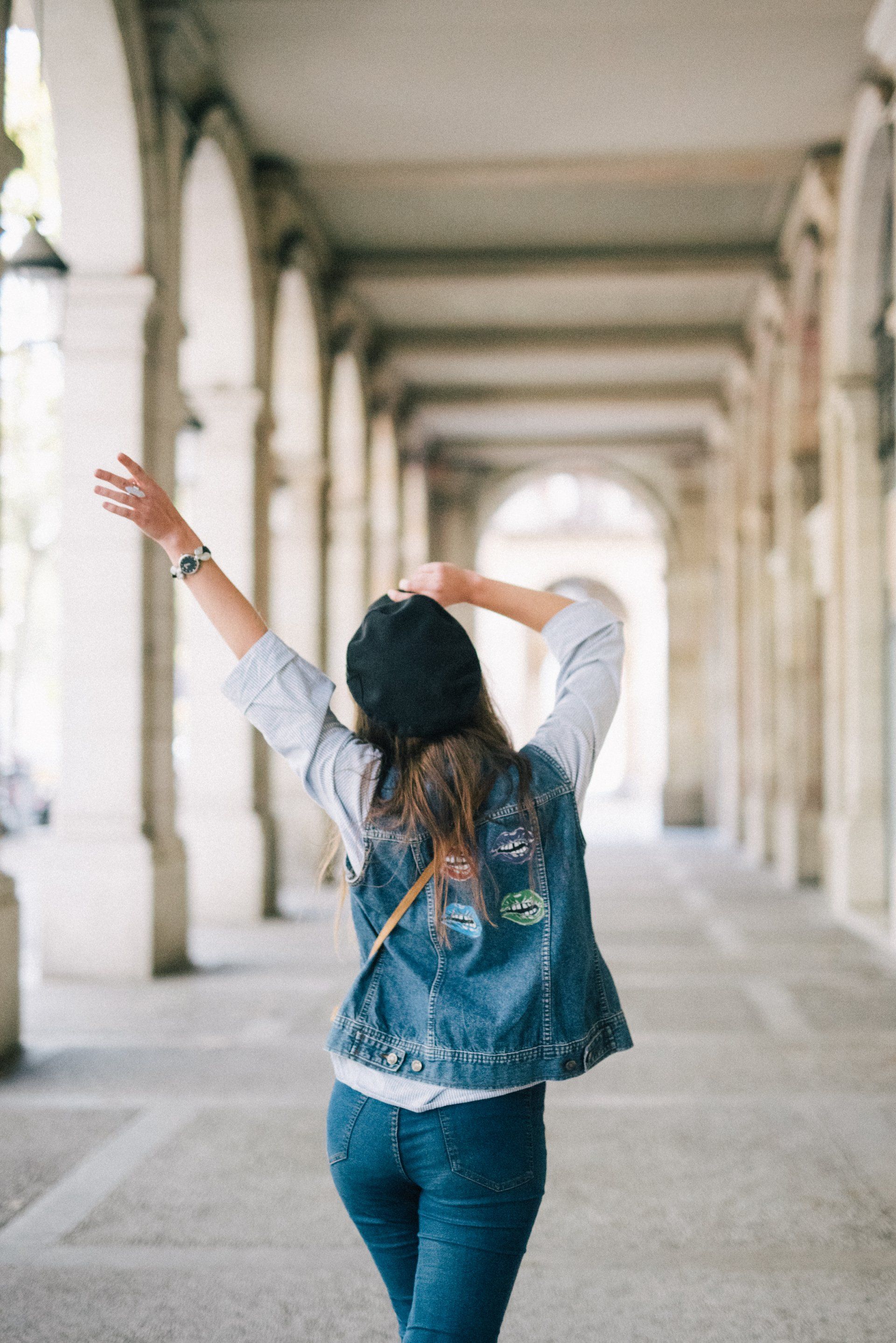 A woman is standing in a hallway with her arms outstretched.