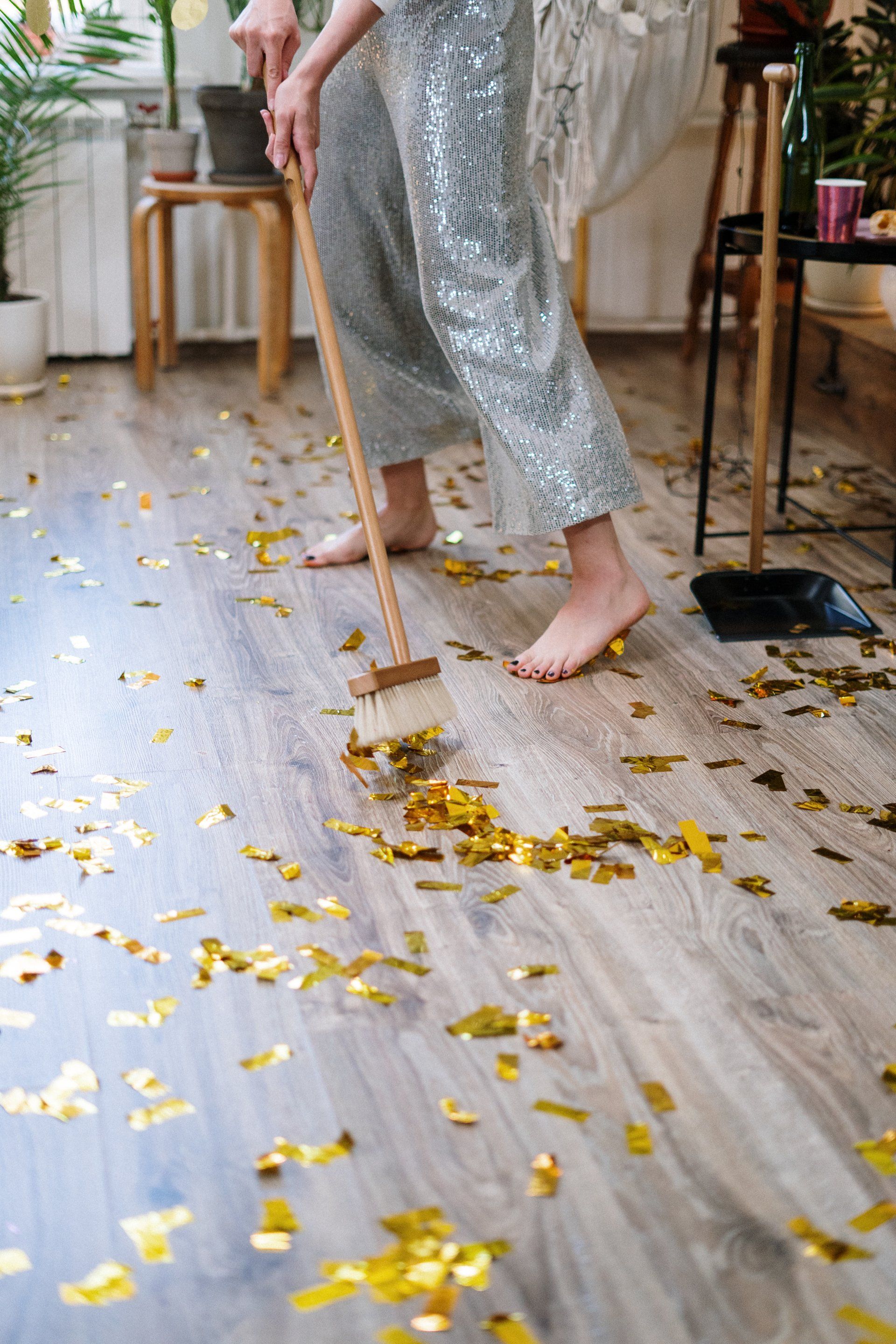A woman in a sequined dress is sweeping the floor with a broom.