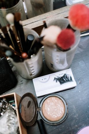 Makeup brushes and powder are on a table in front of a mirror