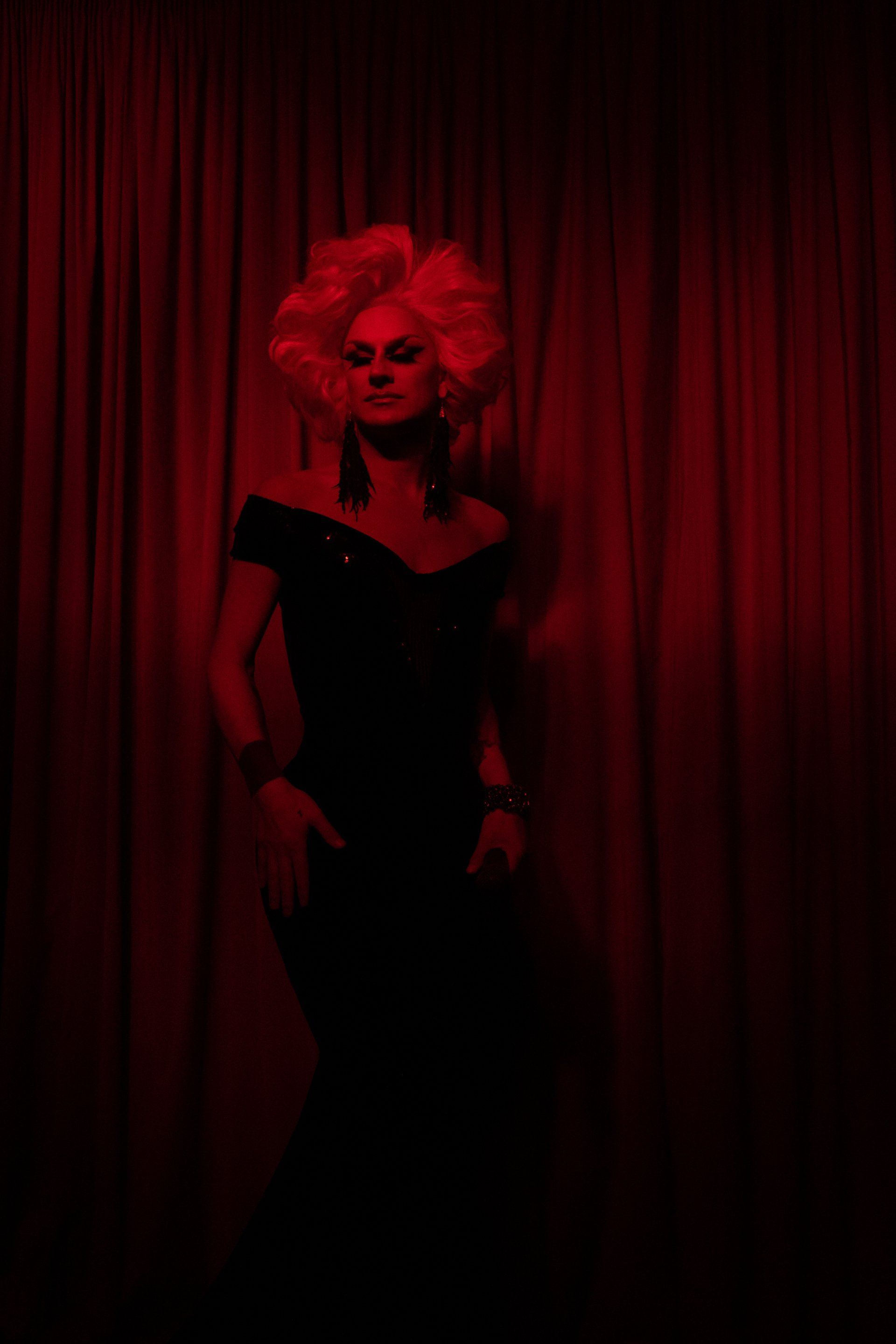 A cabaret performer in front of a red curtain
