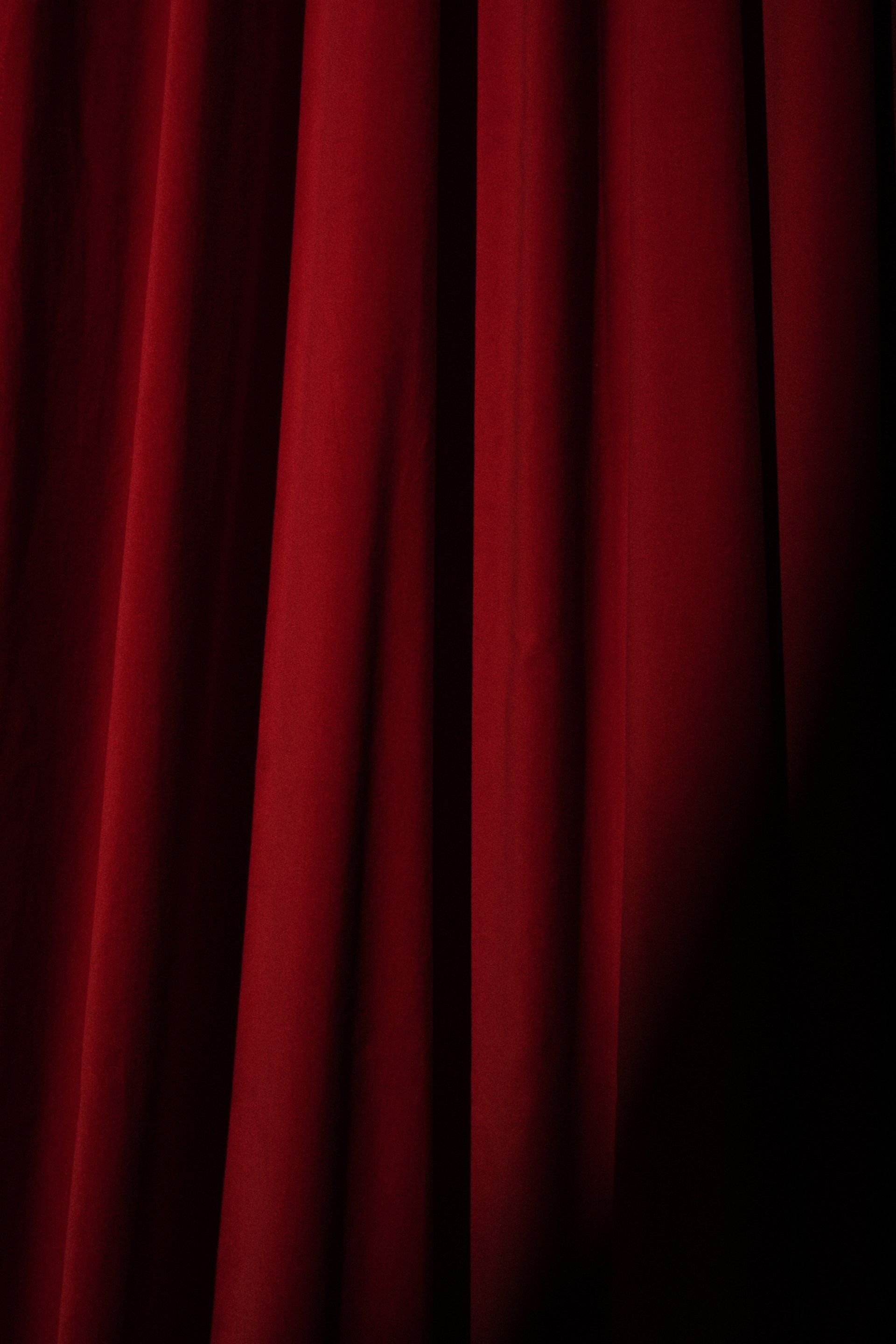 un gros plan d' un rideau rouge de théâtre sur fond noir
