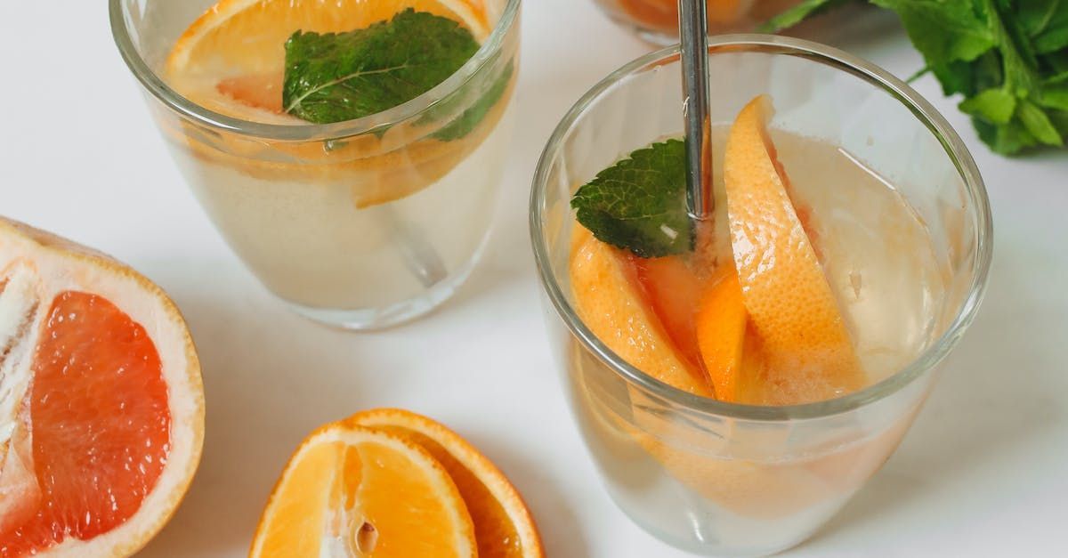 Two glasses of water with grapefruit slices and mint leaves.