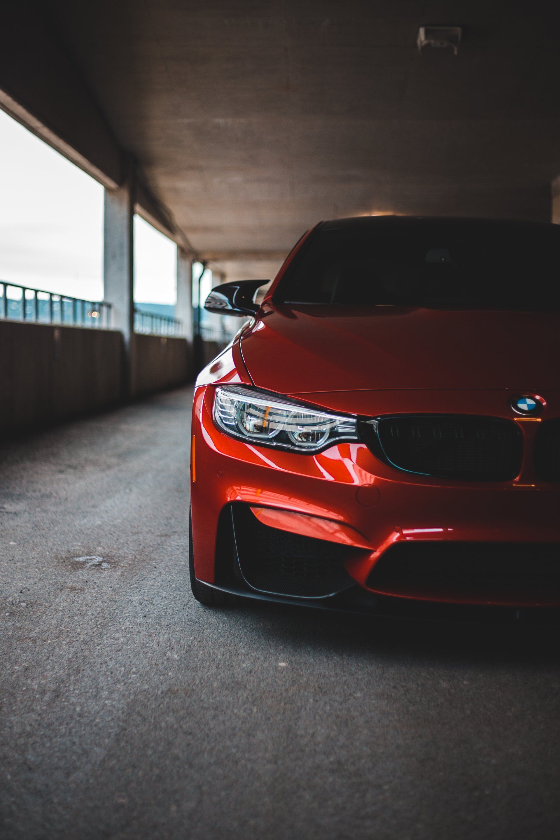 A red bmw m3 is parked in a parking garage.