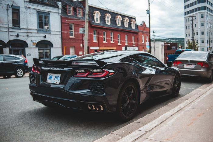 A black sports car is parked on the side of the road in front of a building.