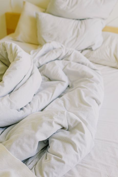 A bed with white sheets and pillows on it.