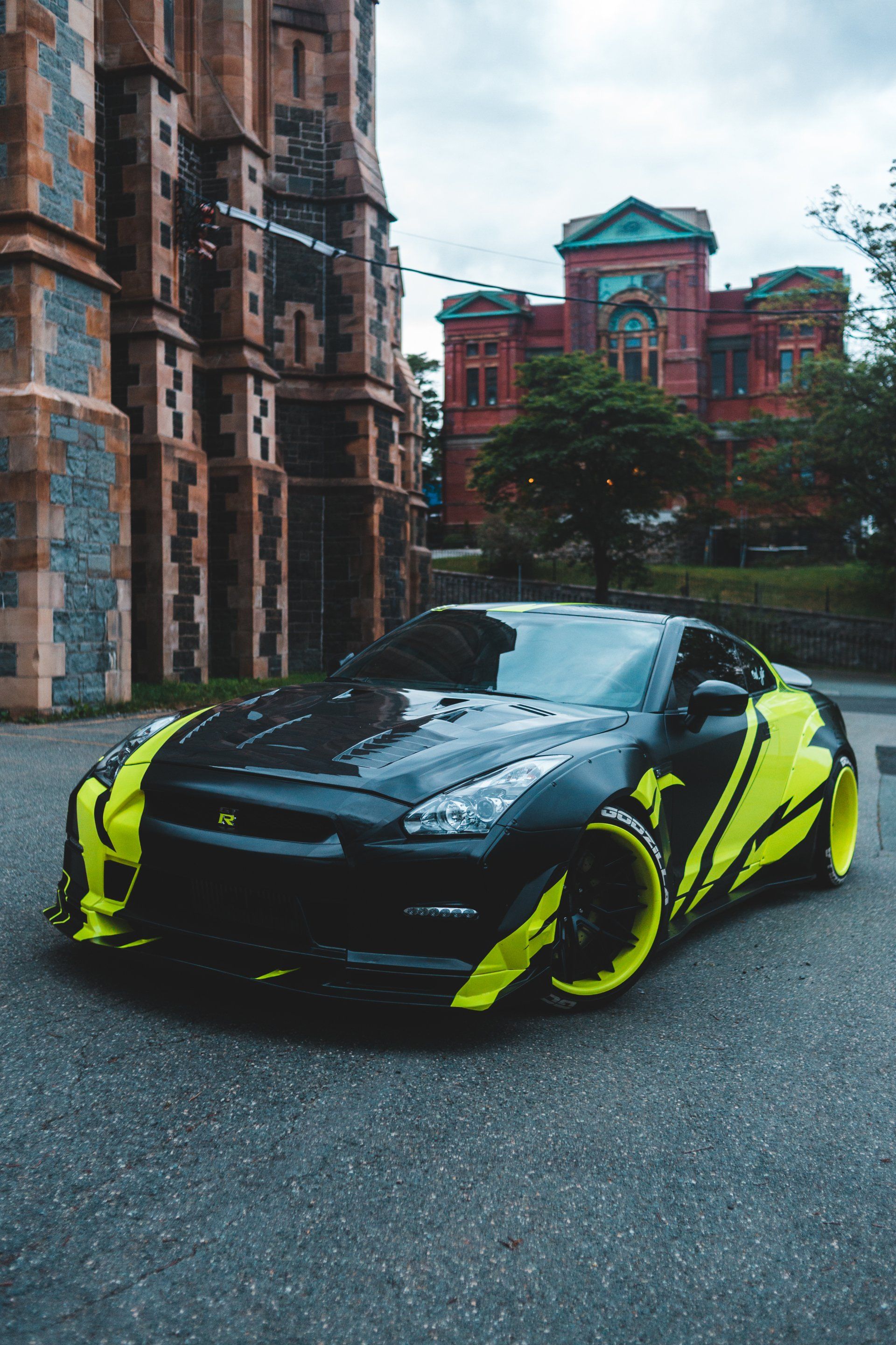 A black and yellow sports car is parked in front of a building.