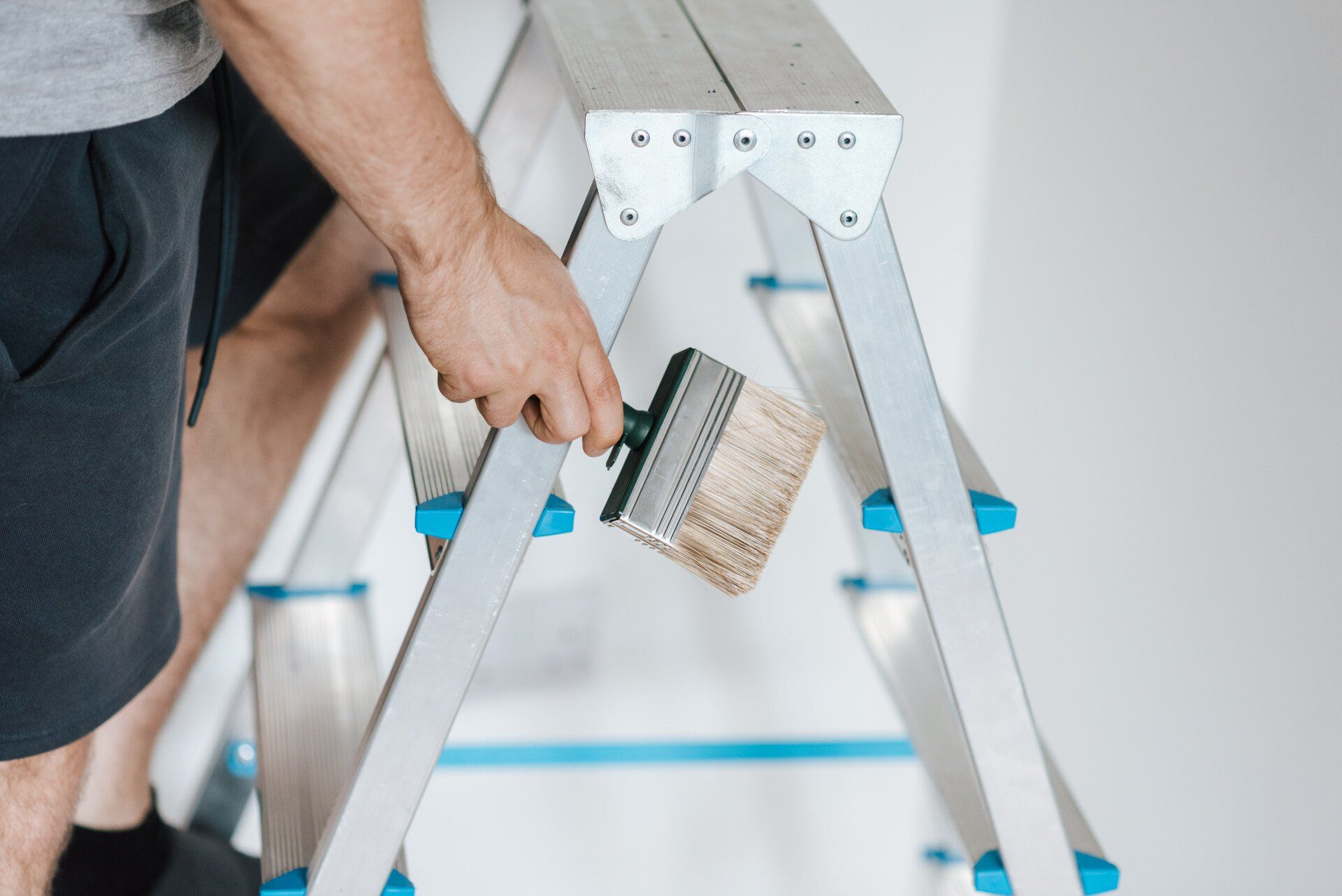 a person holding a paint brush while climbing up a ladder