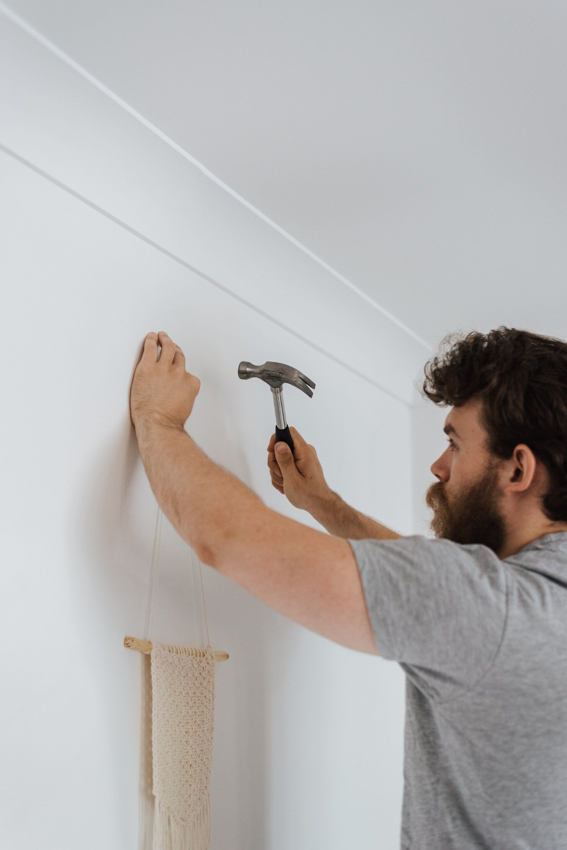 A man is hammering a nail into a wall.