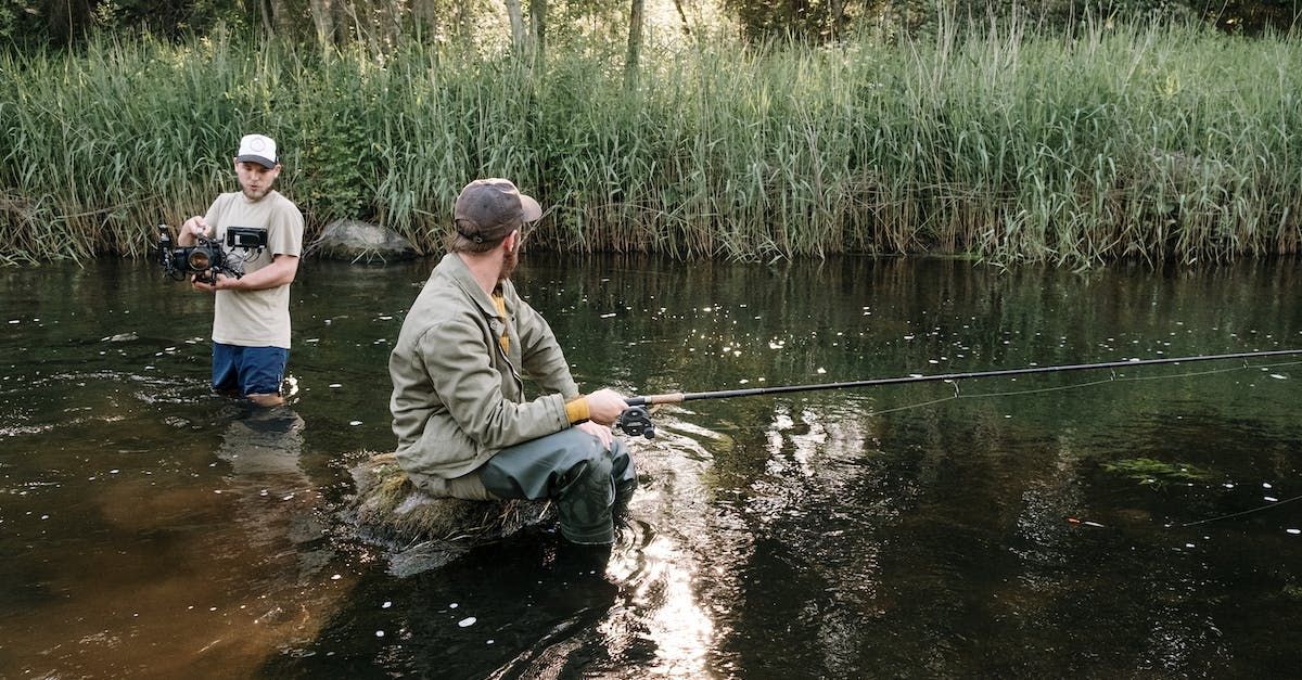 A man and a boy are fishing in a river.