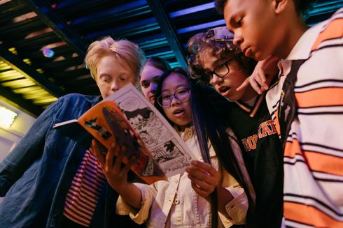 A group of young people are looking at a book together.