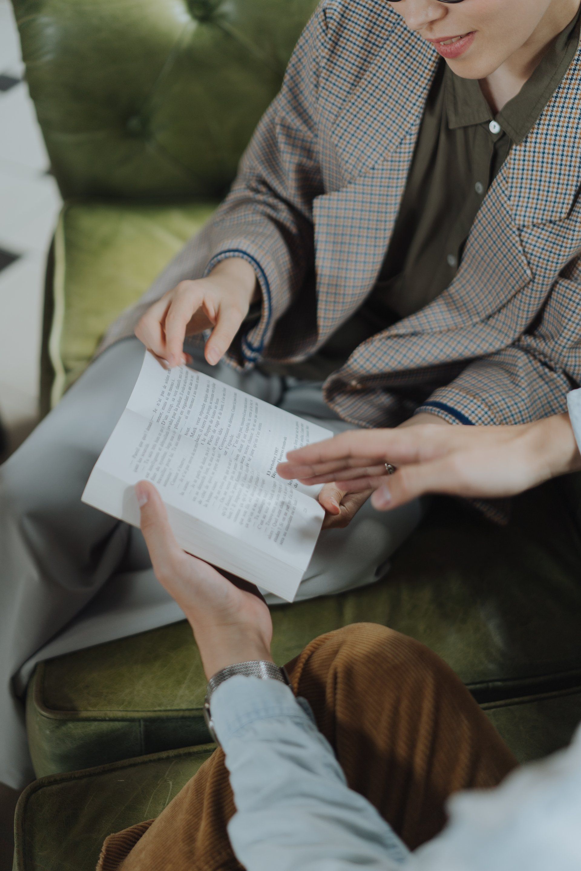 A man and a woman are sitting on a couch looking at a piece of paper.