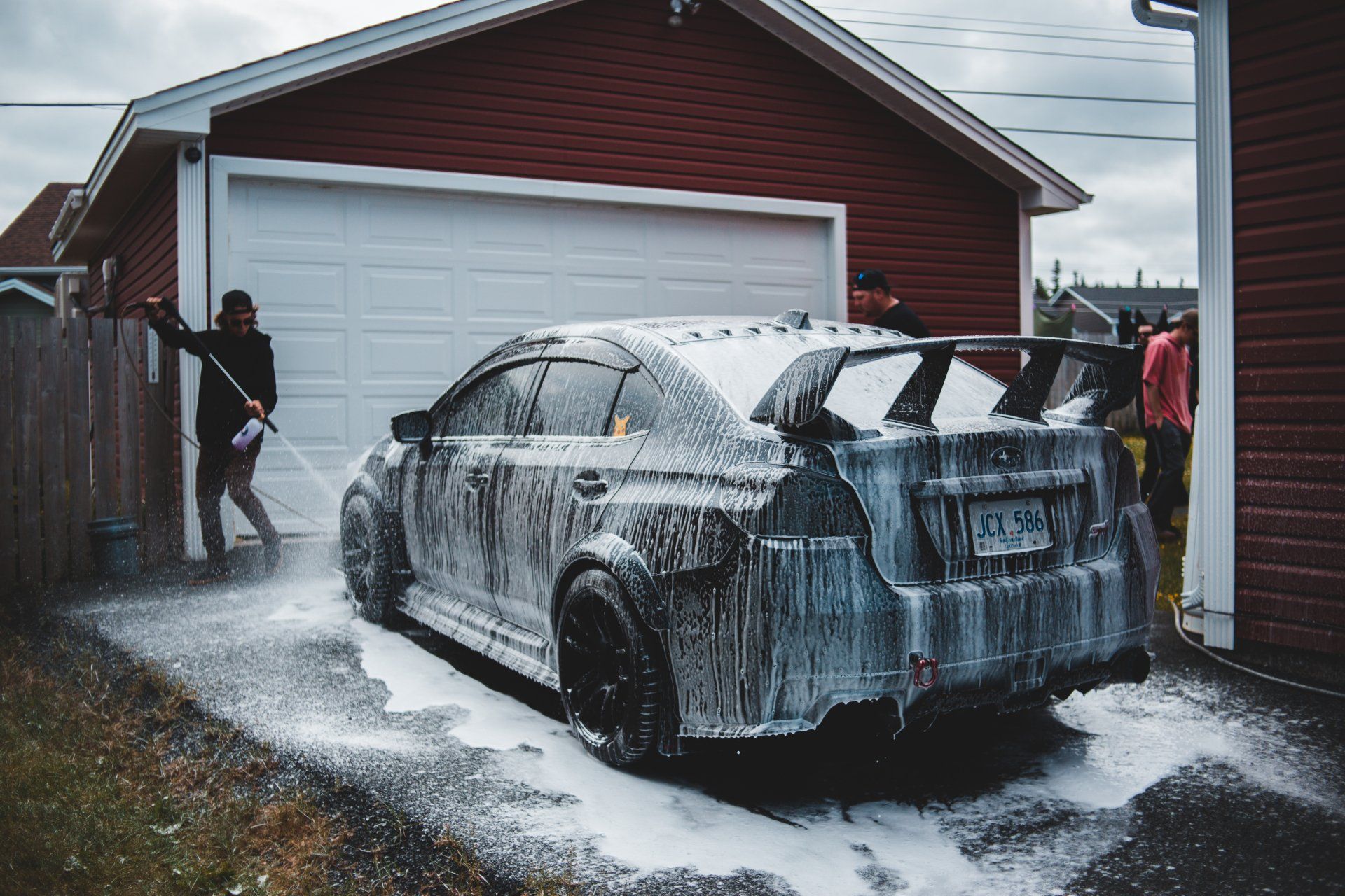a man power washing a vehicle in the garage