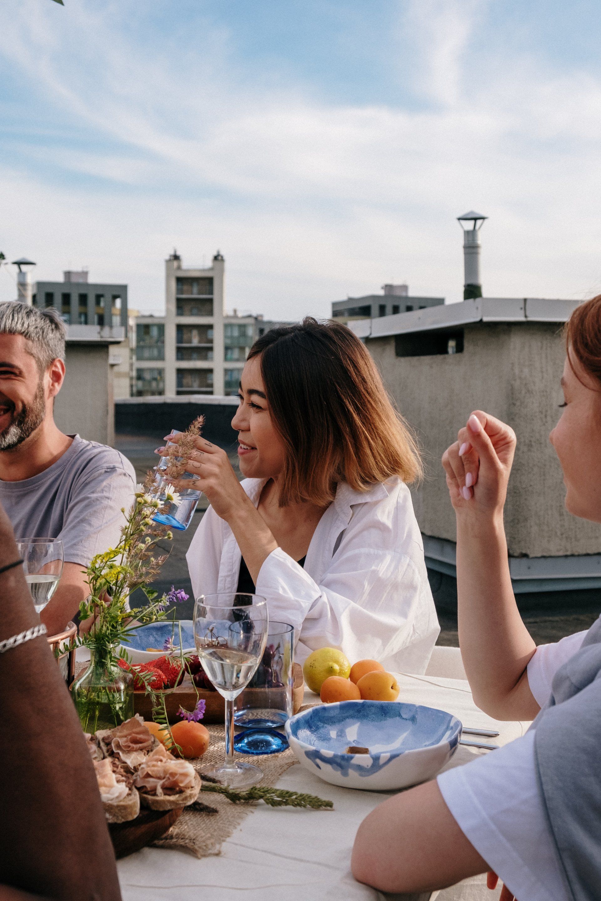 A group of people are sitting at a table eating food and drinking wine.