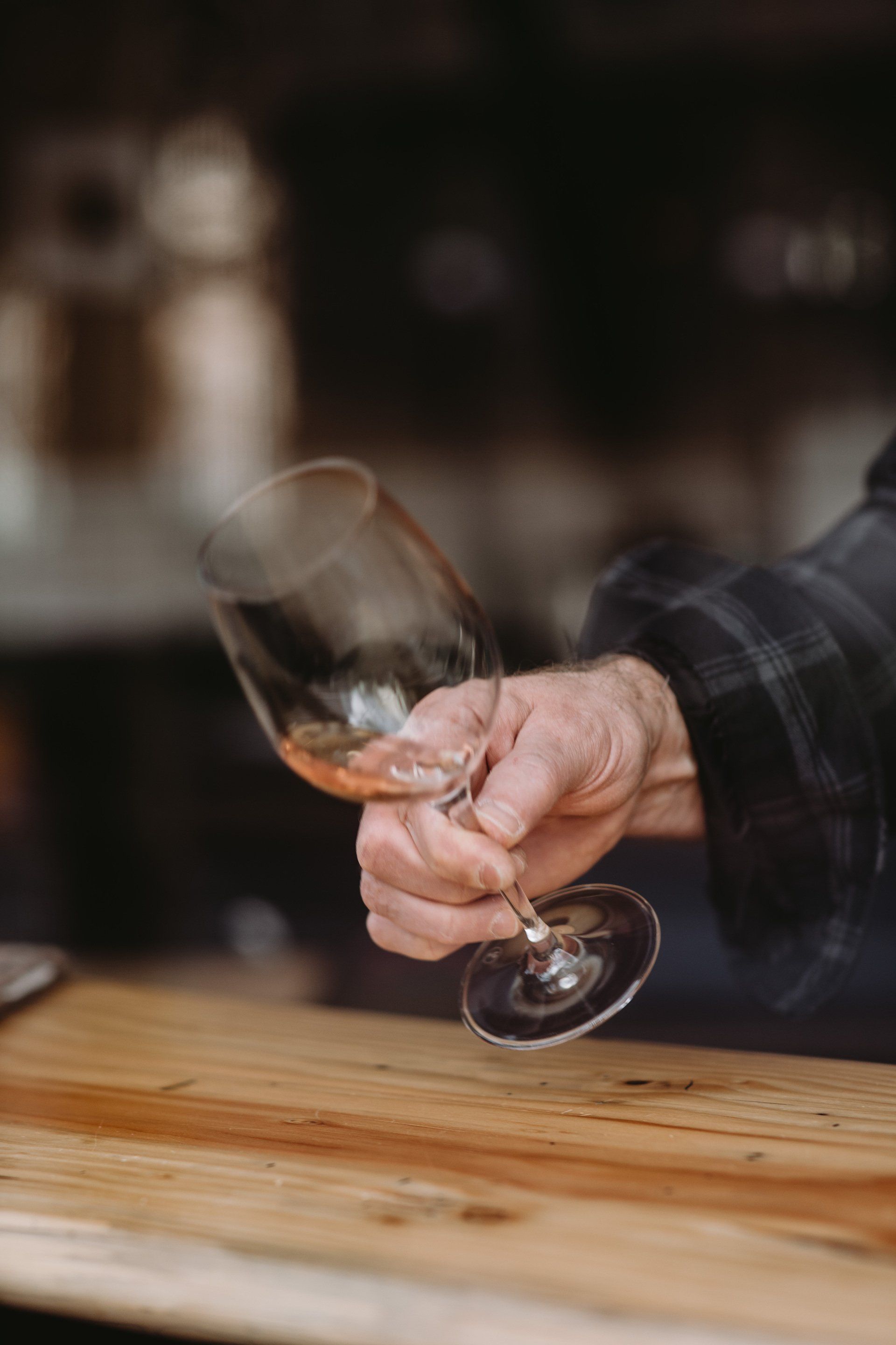 A person is holding a wine glass on a wooden table.