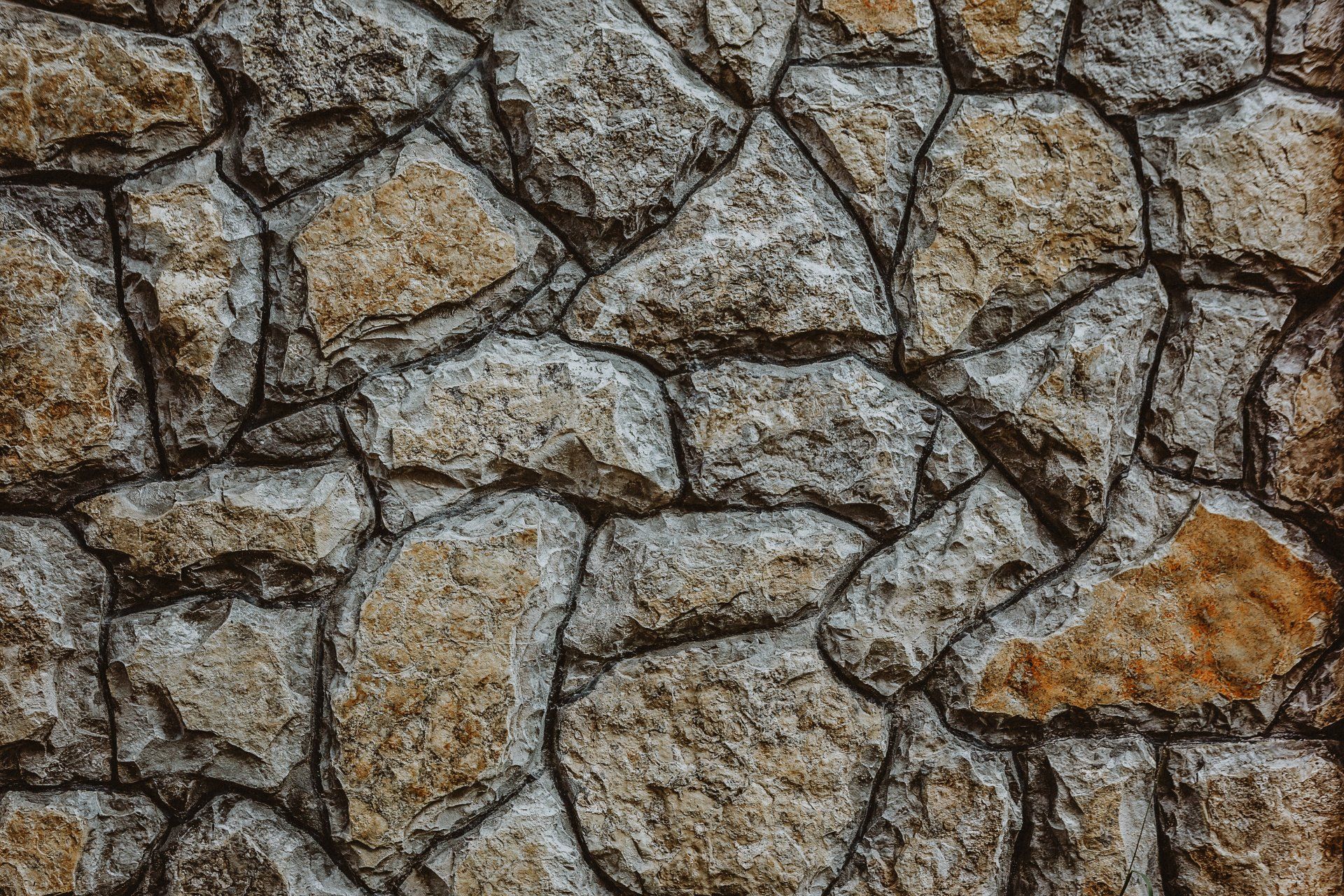 Close-up of a rustic stone wall texture, showcasing the natural patterns and earthy colors of the stones.