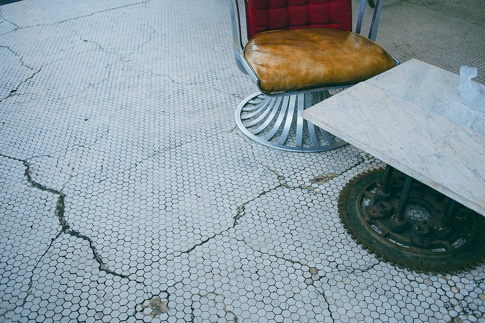 a cracked tile floor with a chair and a table