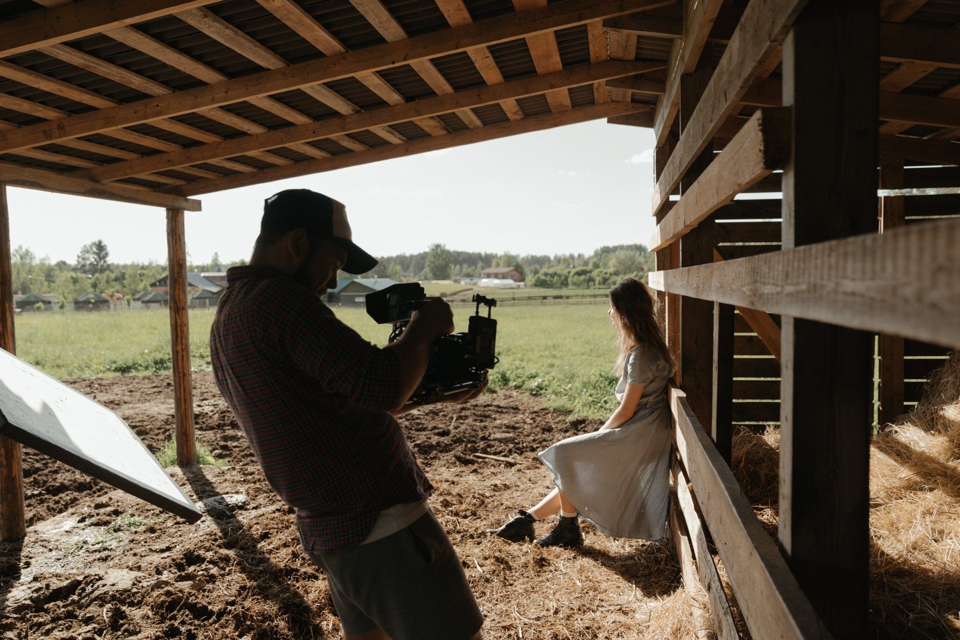 A man is taking a picture of a woman sitting in a barn.