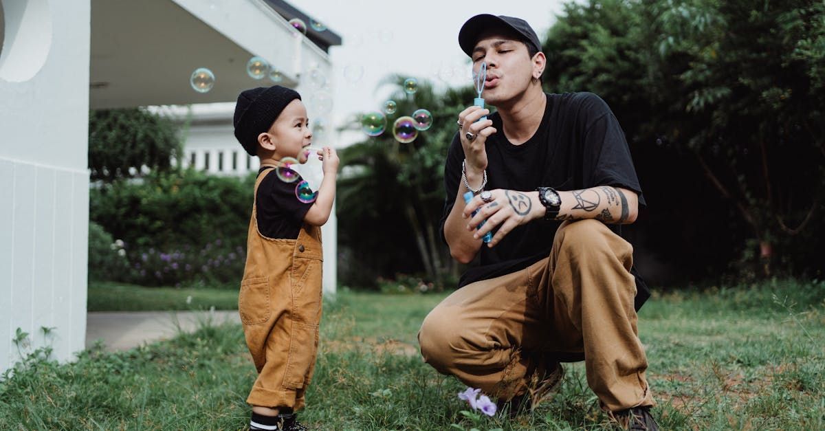 A man and a little boy are blowing soap bubbles in the grass.