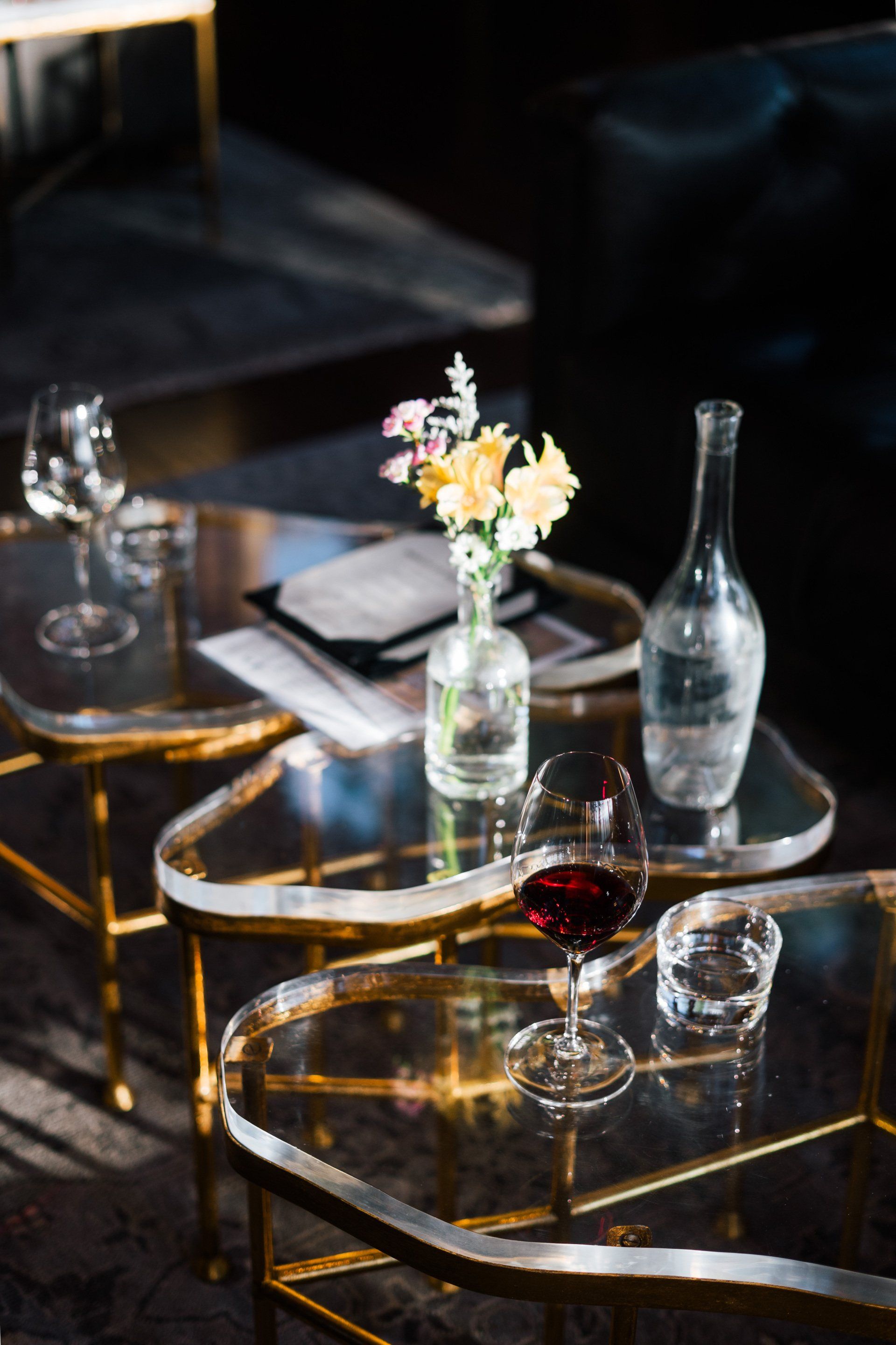 A table with a vase of flowers and a glass of wine on it.