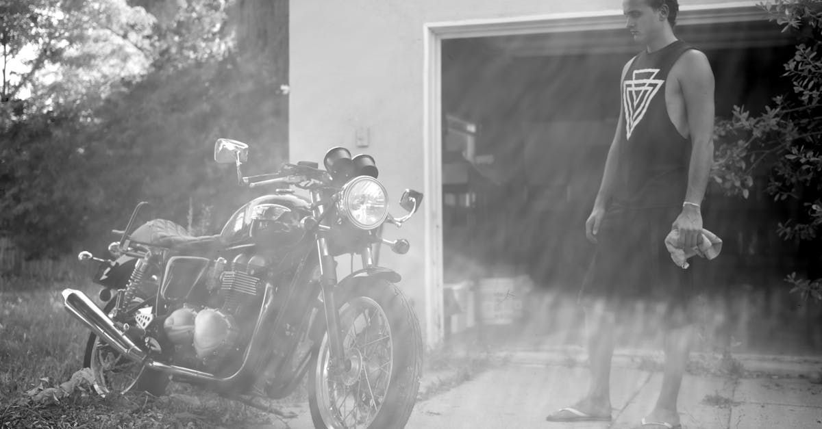 A man is standing in front of a motorcycle in a black and white photo.