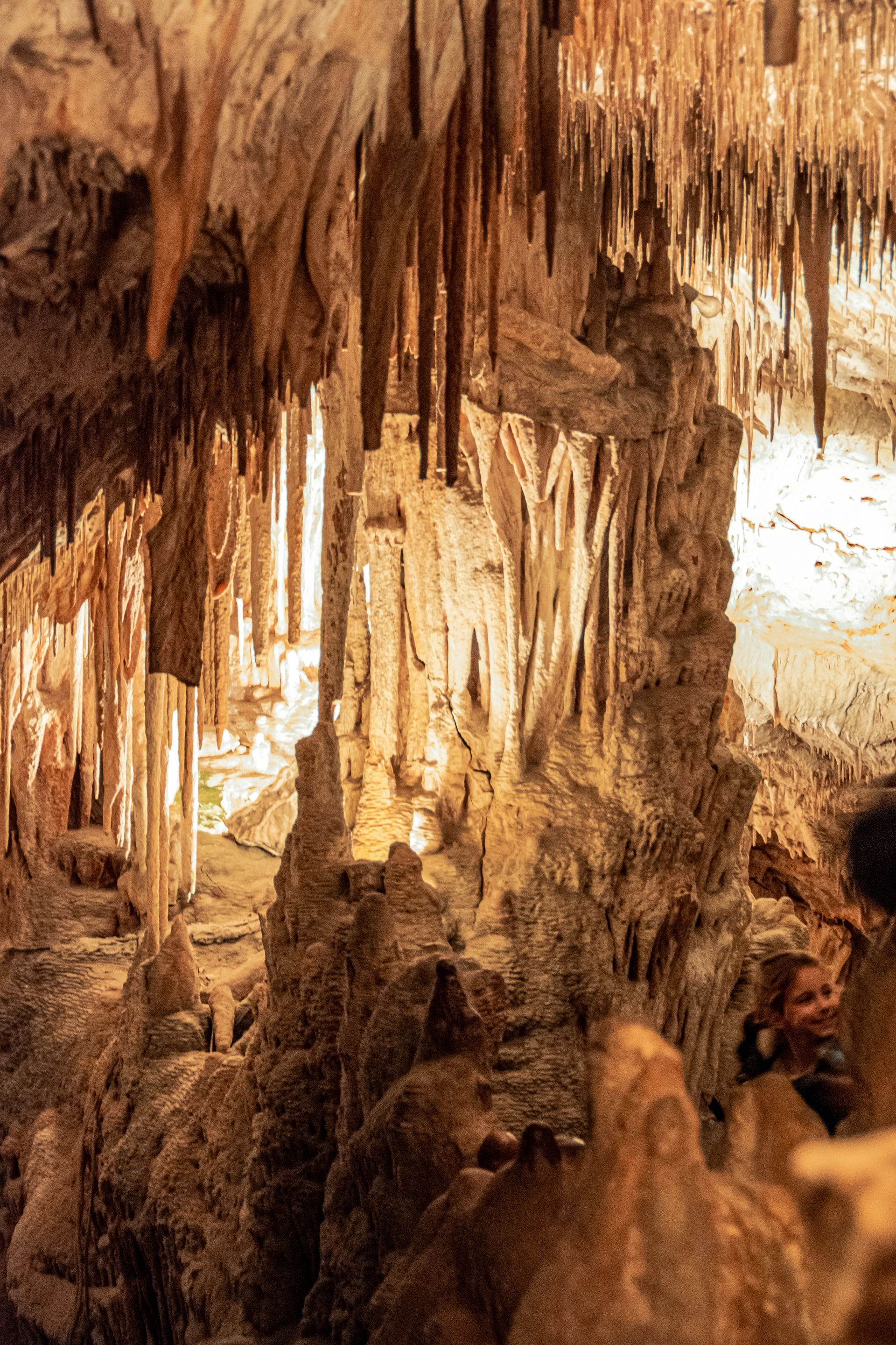 A person is standing in a cave with a lot of icicles hanging from the ceiling.