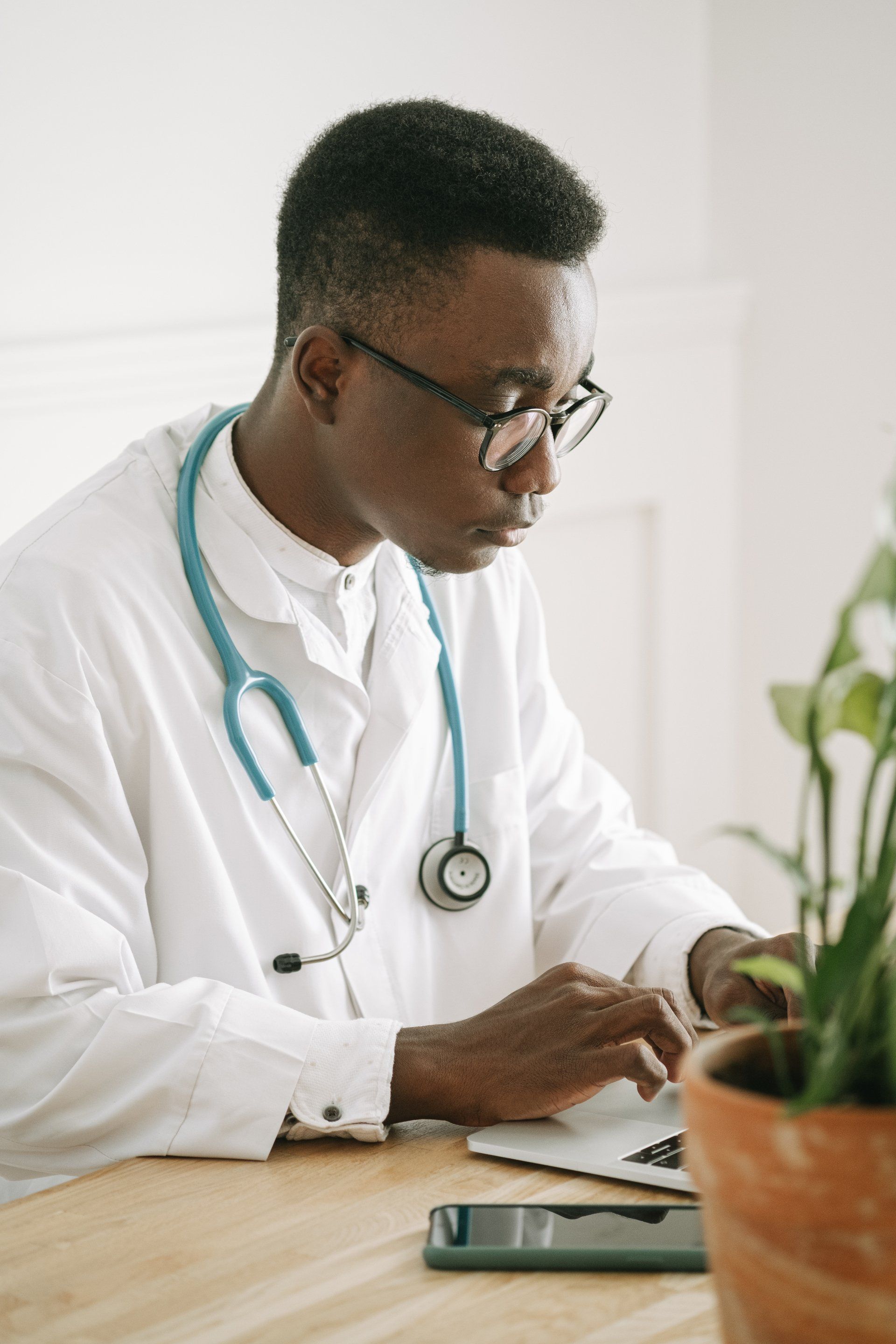 a doctor with a stethoscope around his neck is sitting at a desk .