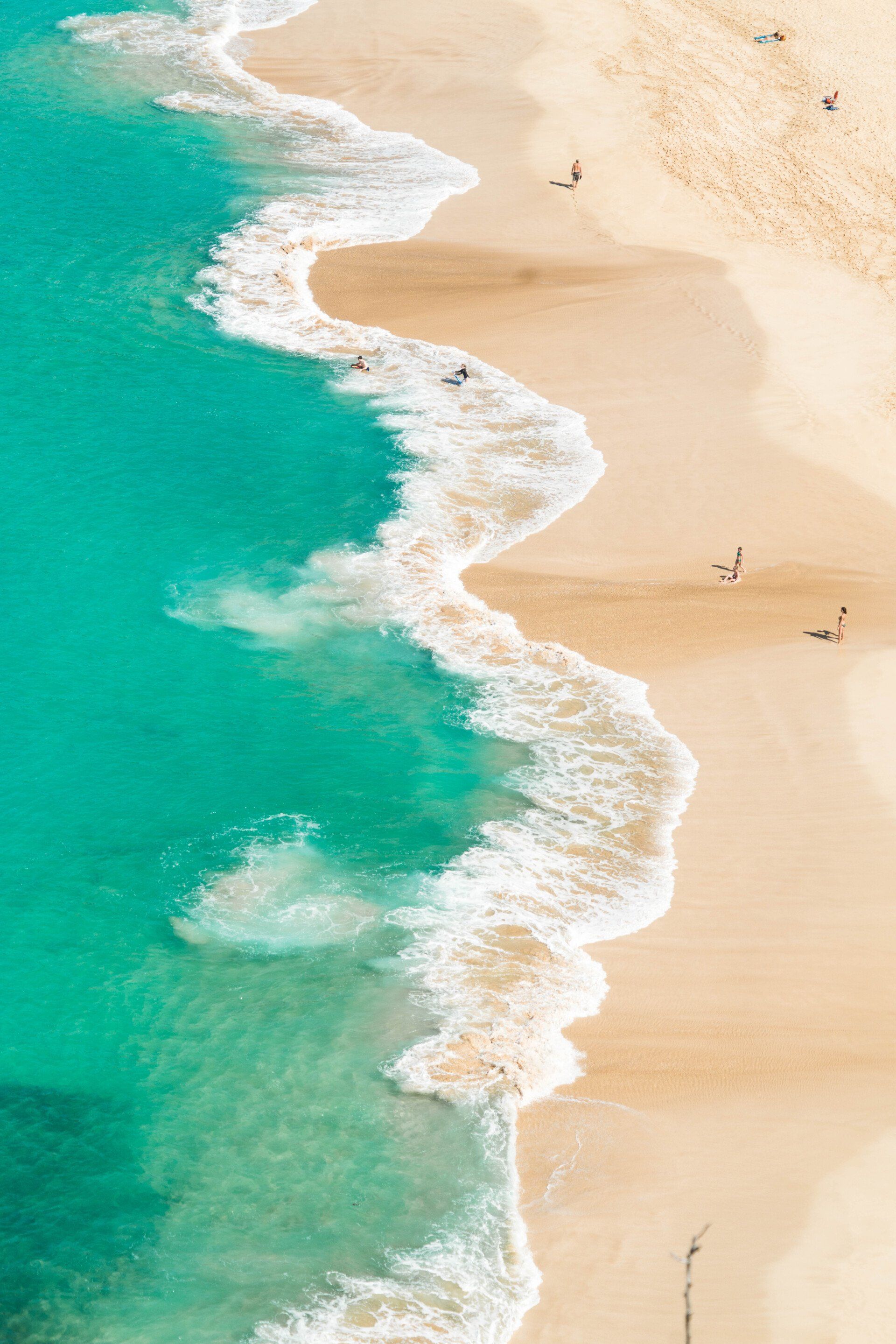 An aerial view of a beach with waves crashing on the sand