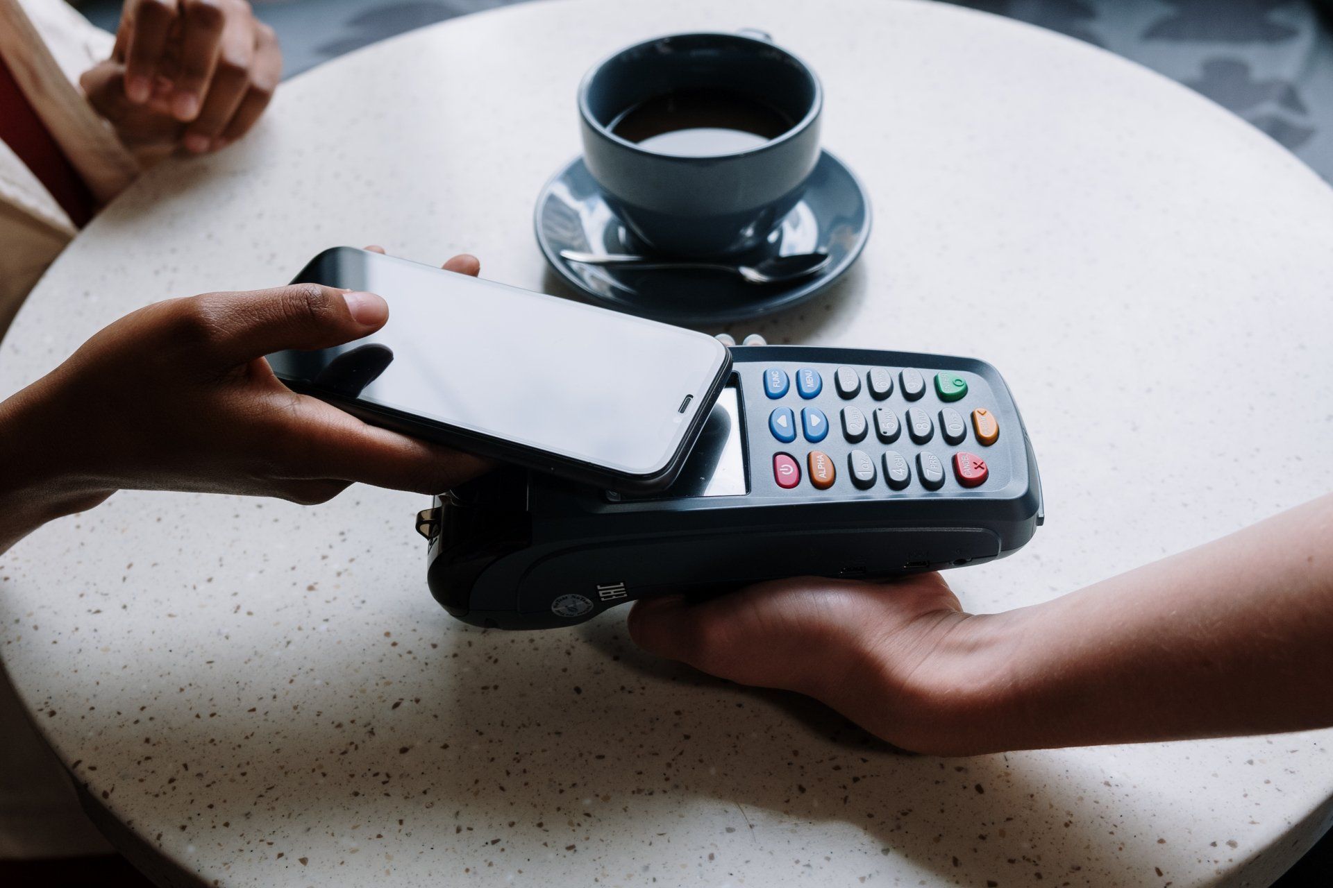 a person is using a credit card to pay for a cup of coffee .