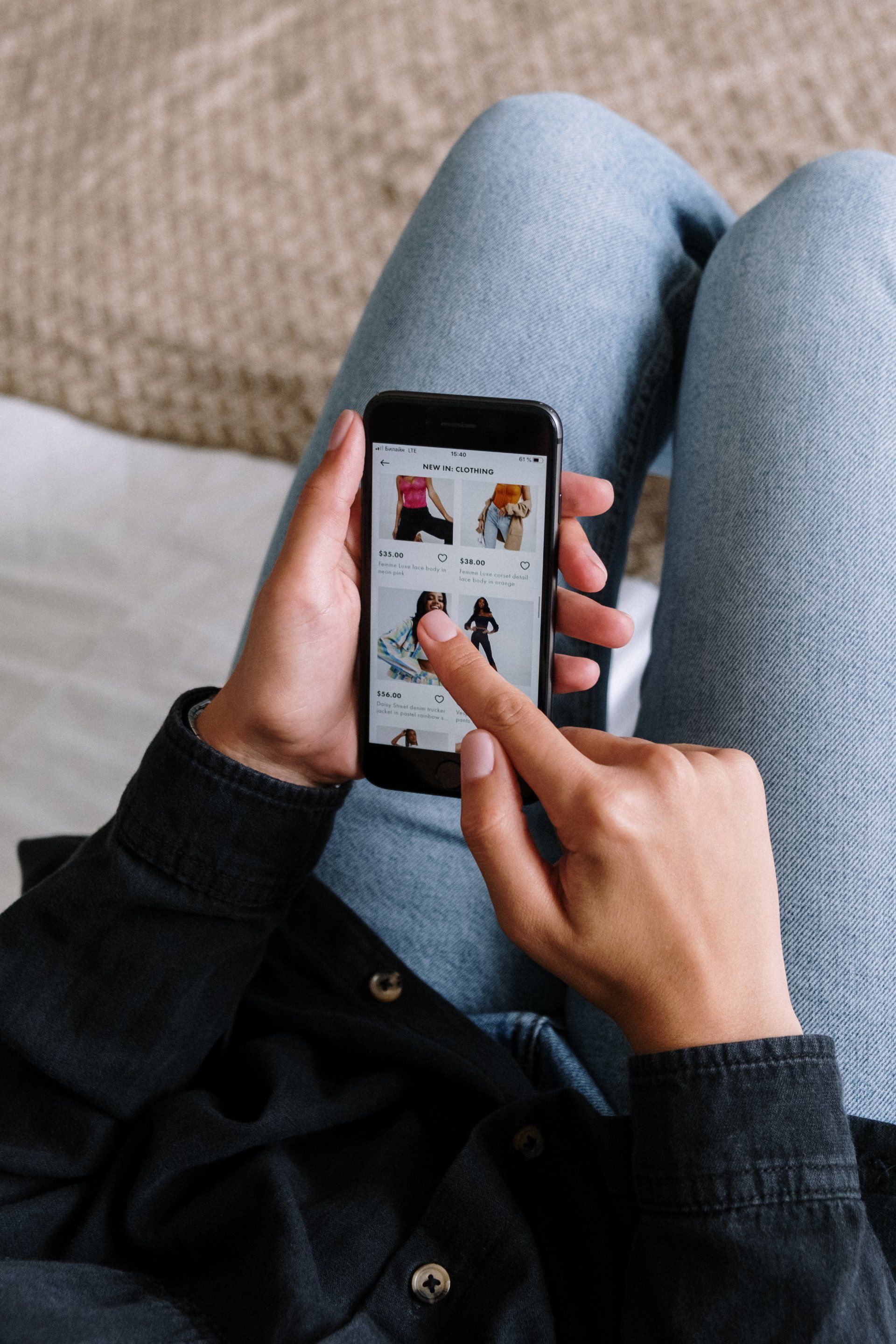 a person is sitting on a bed using a cell phone to shop online