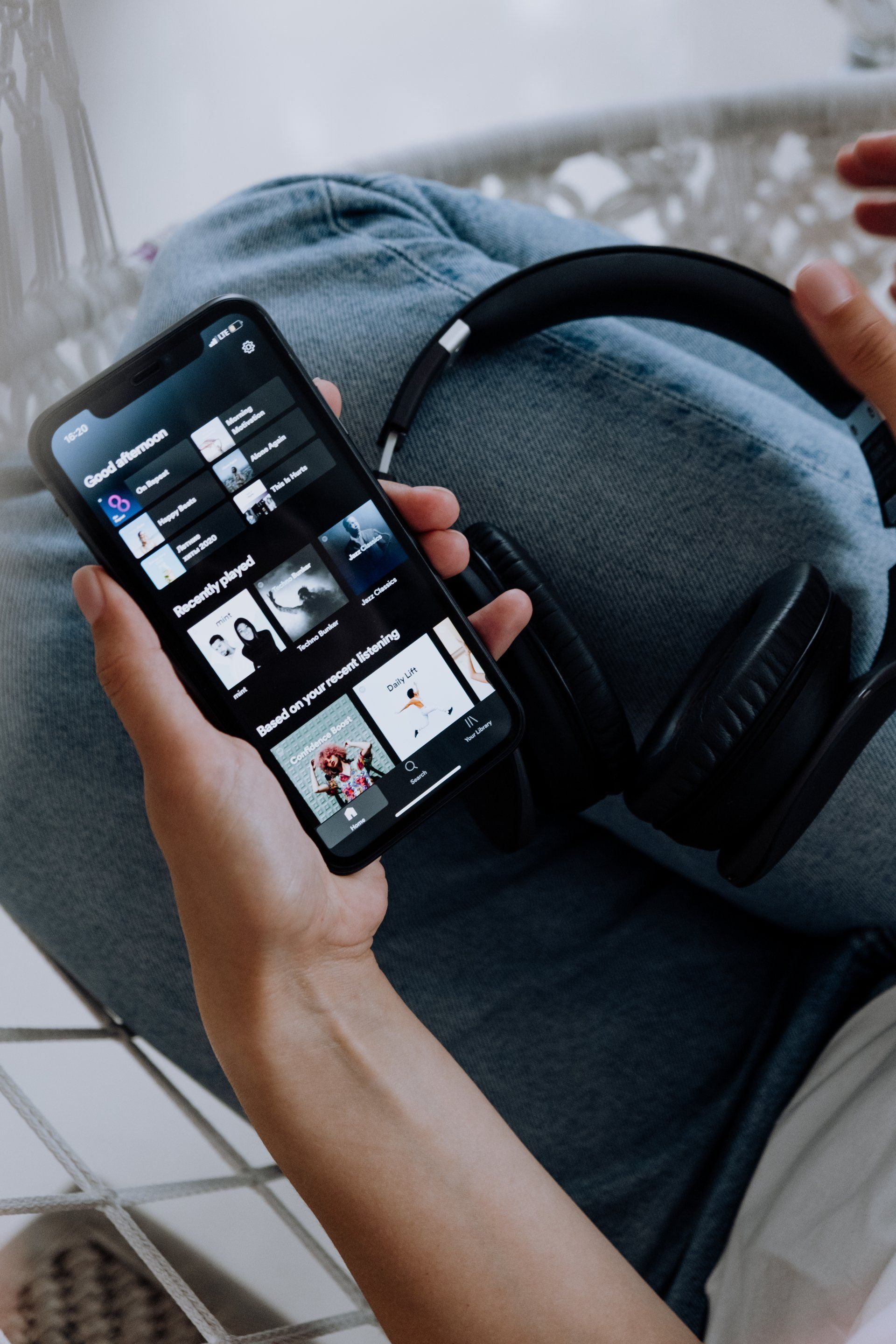 A person is holding a cell phone and headphones in their hands.