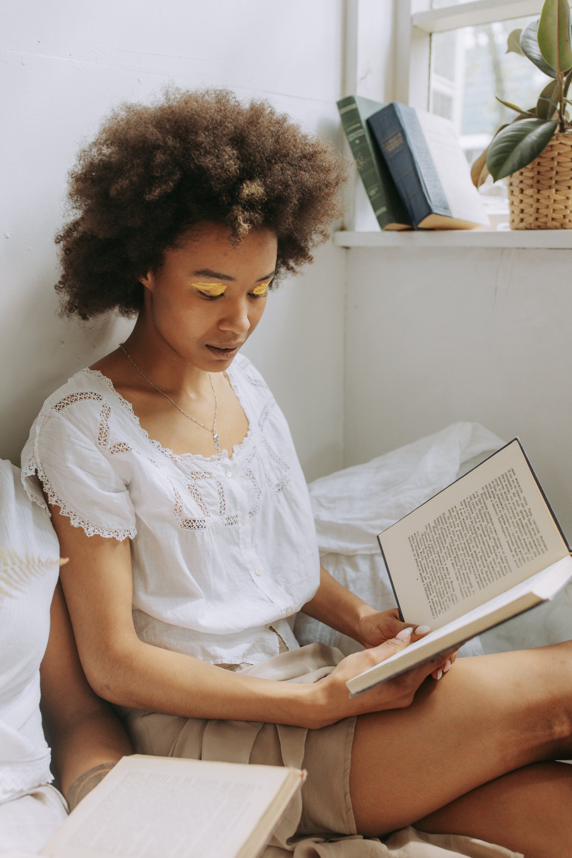 A woman is sitting on a bed reading a book.