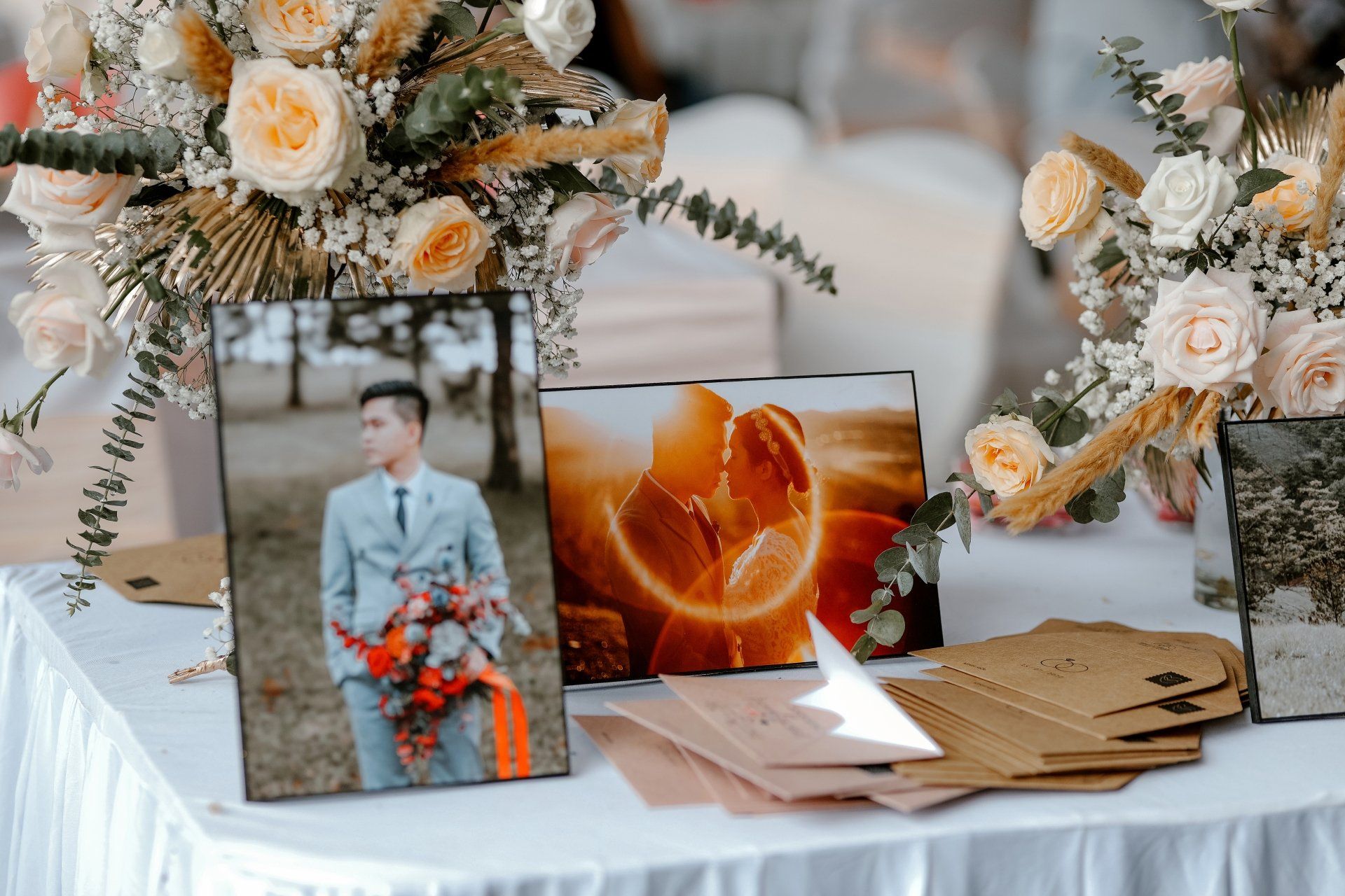 a table with a vase of flowers and a picture of a bride and groom on it .