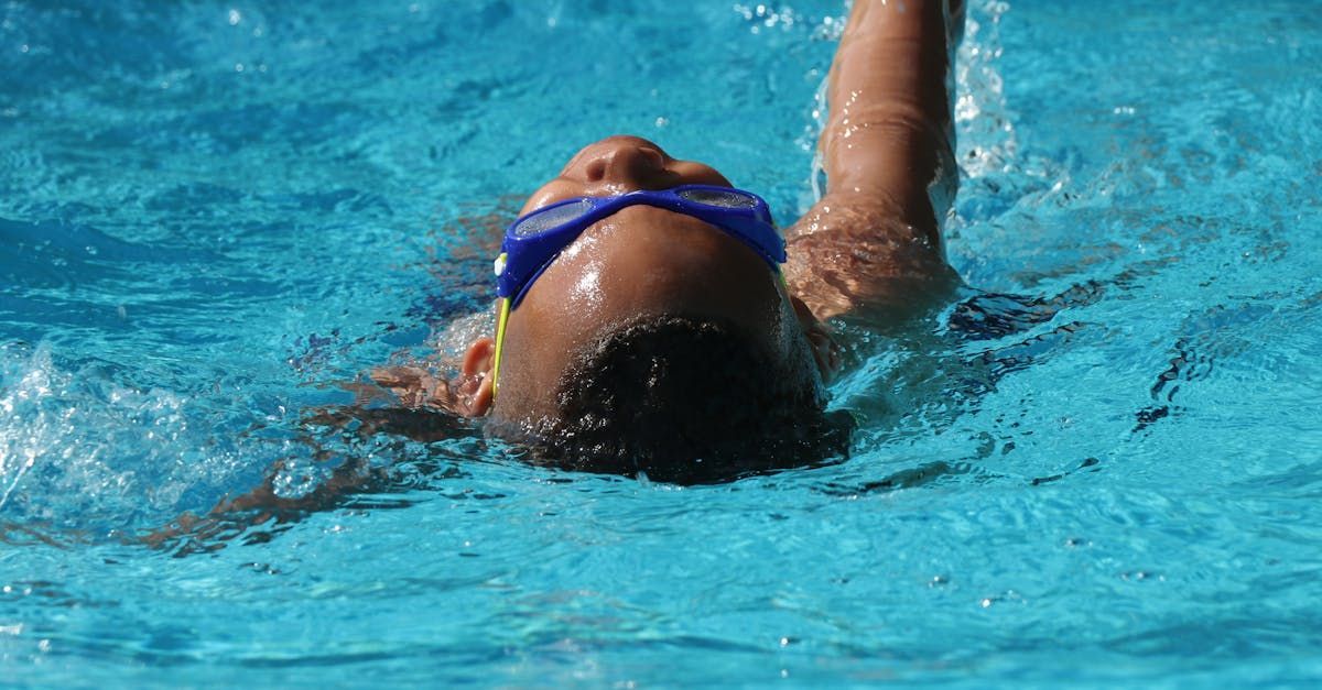A young boy wearing goggles is swimming in a swimming pool.