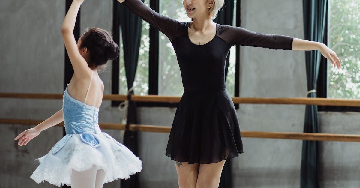 A woman is teaching a young girl how to dance ballet in a dance studio.