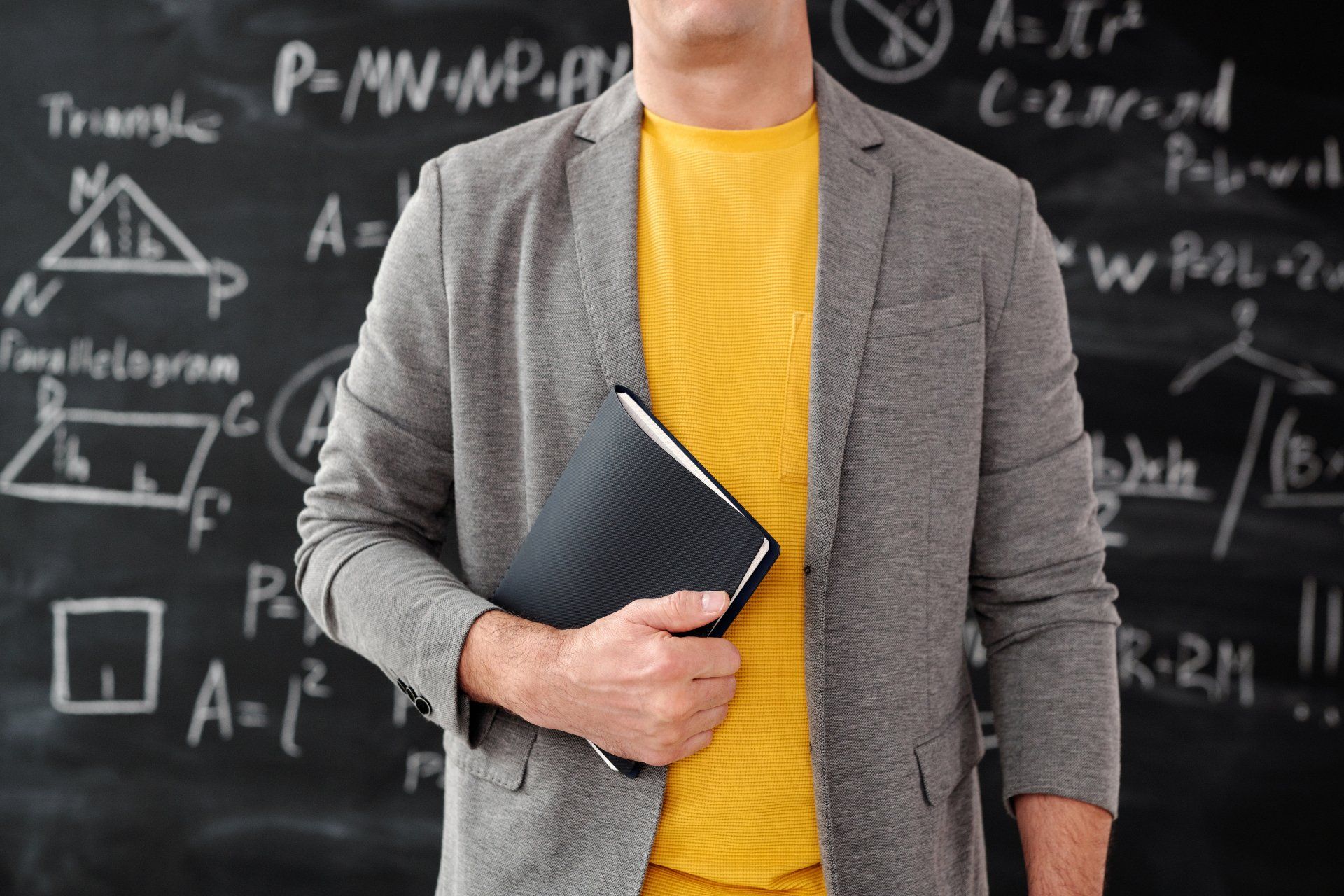 a man is standing in front of a blackboard holding a book .