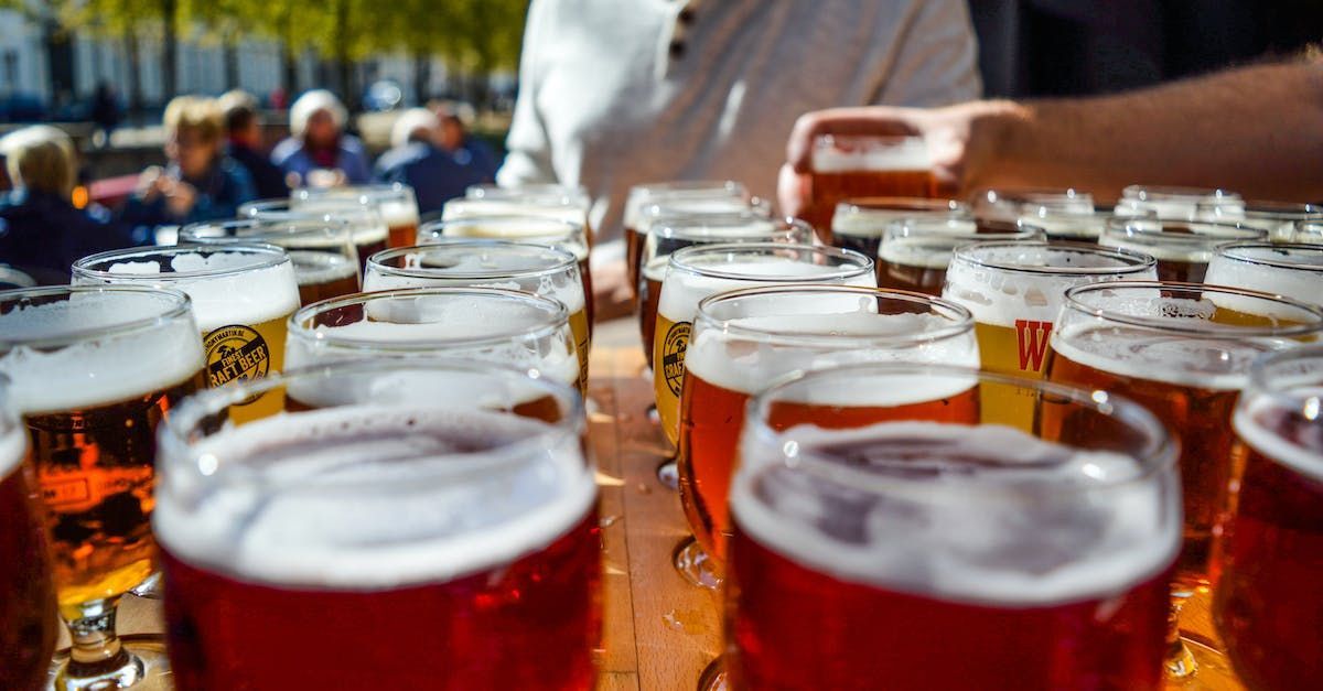 A row of glasses of beer are lined up on a table.