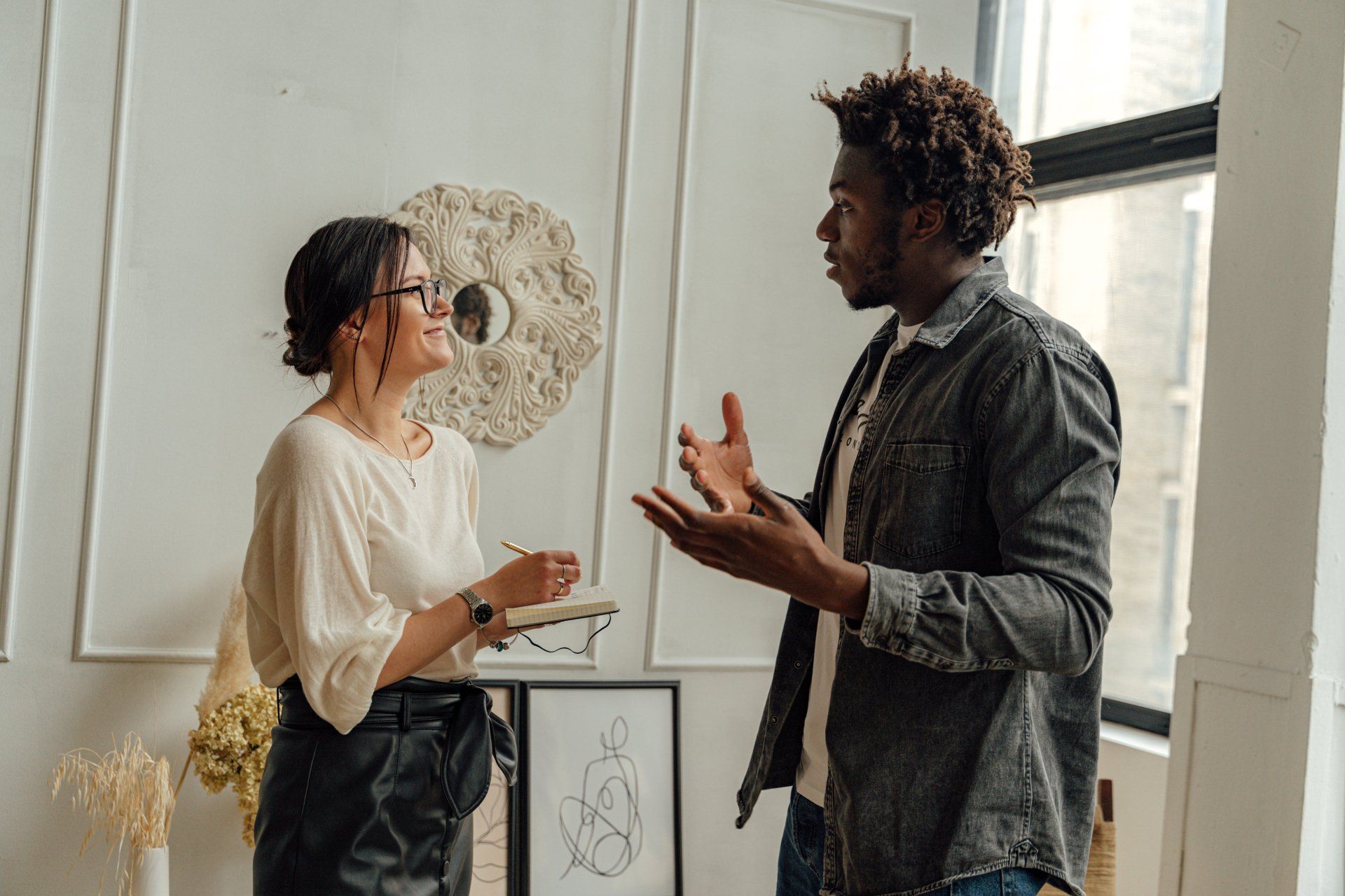 A man and a woman are talking to each other in a living room.