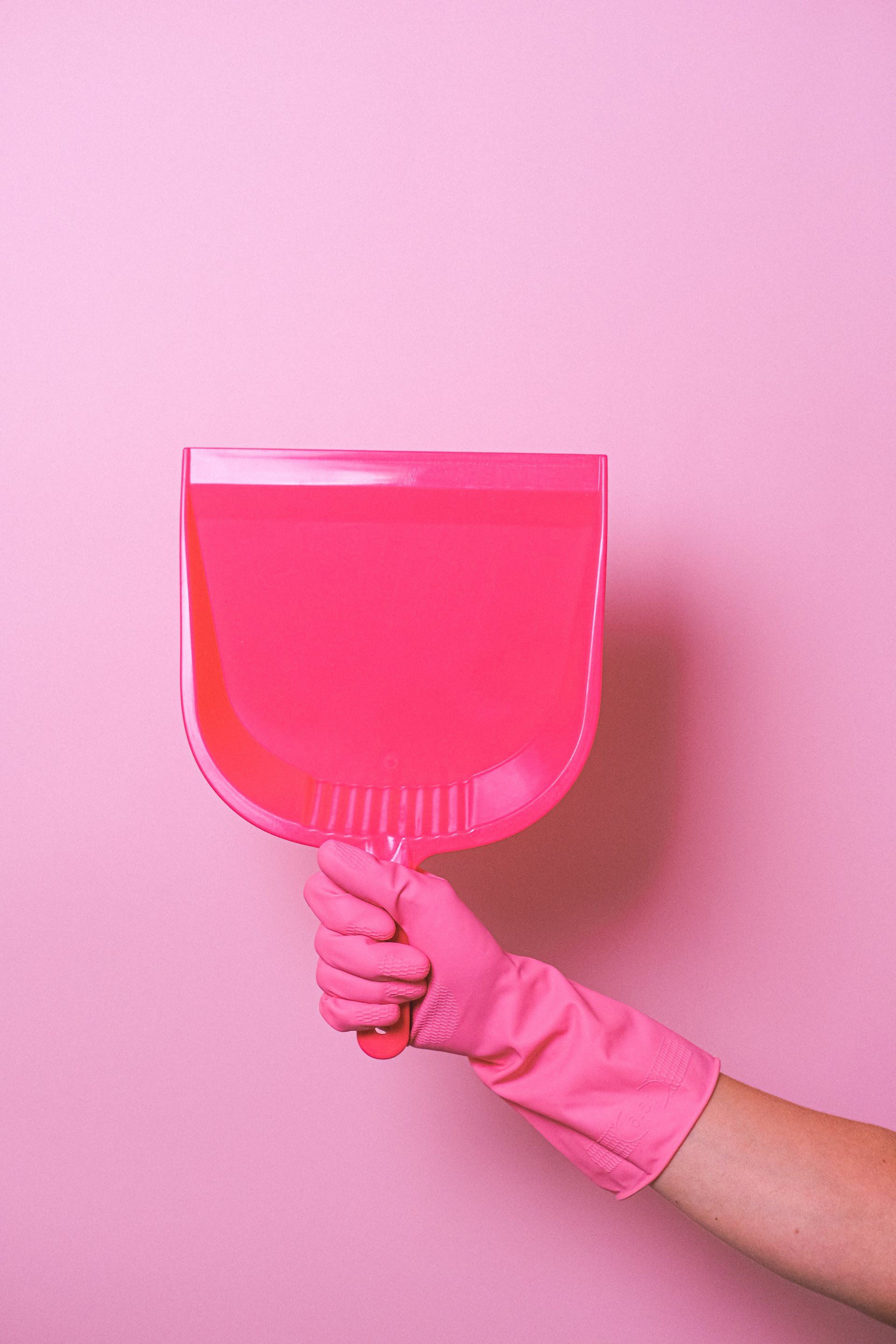 House cleaner holding a pink dustpan for cleaning