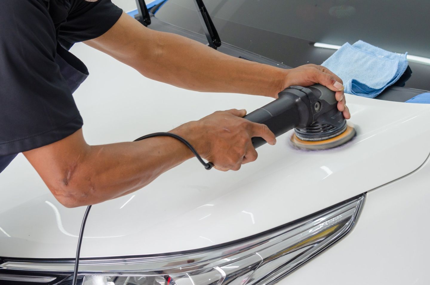 a man is polishing a white car with a machine .