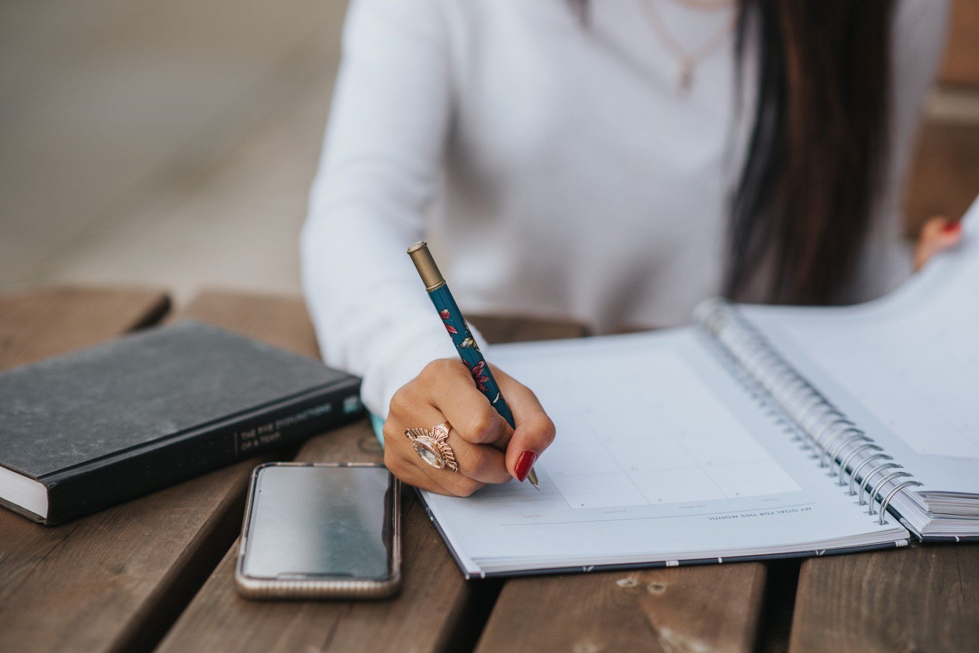 A woman is sitting at a table writing in a notebook.
